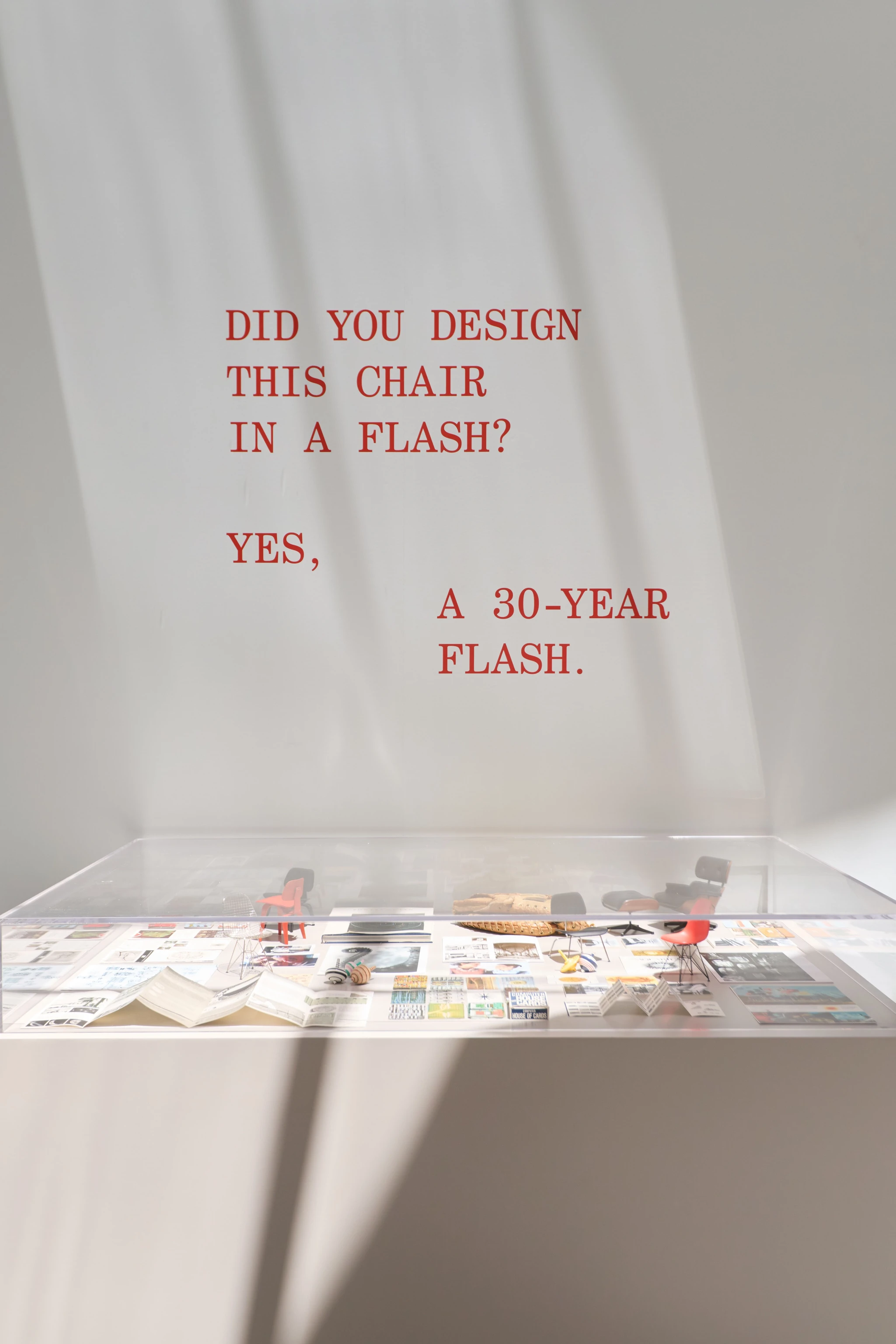 The Past as Prologue exhibition at the Transamerica Pyramid Annex Gallery featuring a glass case with several mini Eames chairs and a quote from Charles Eames.