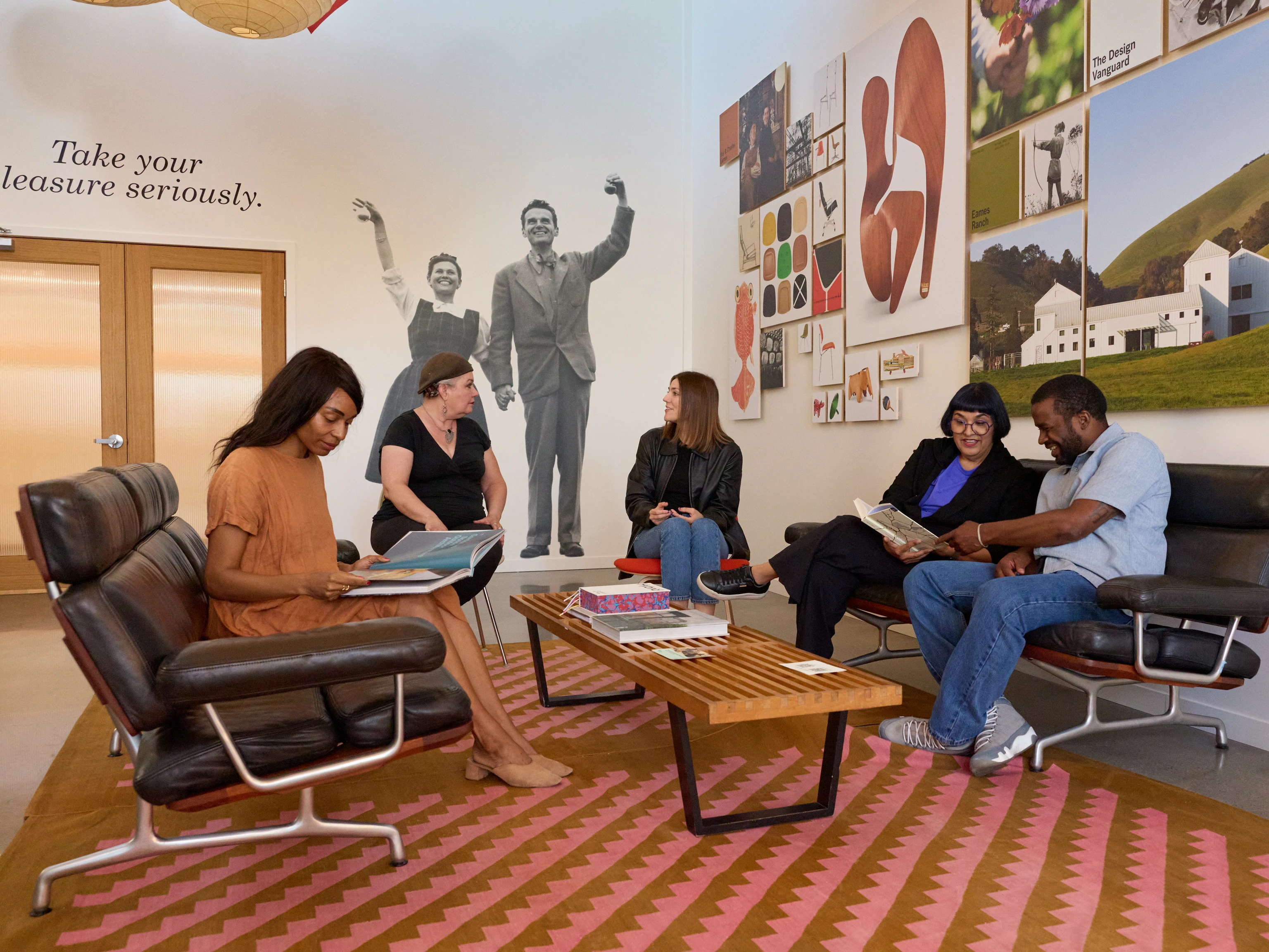 Visitors browse books in the Eames Institute Welcome Center, surrounded by design objects, and Eames furnishings.