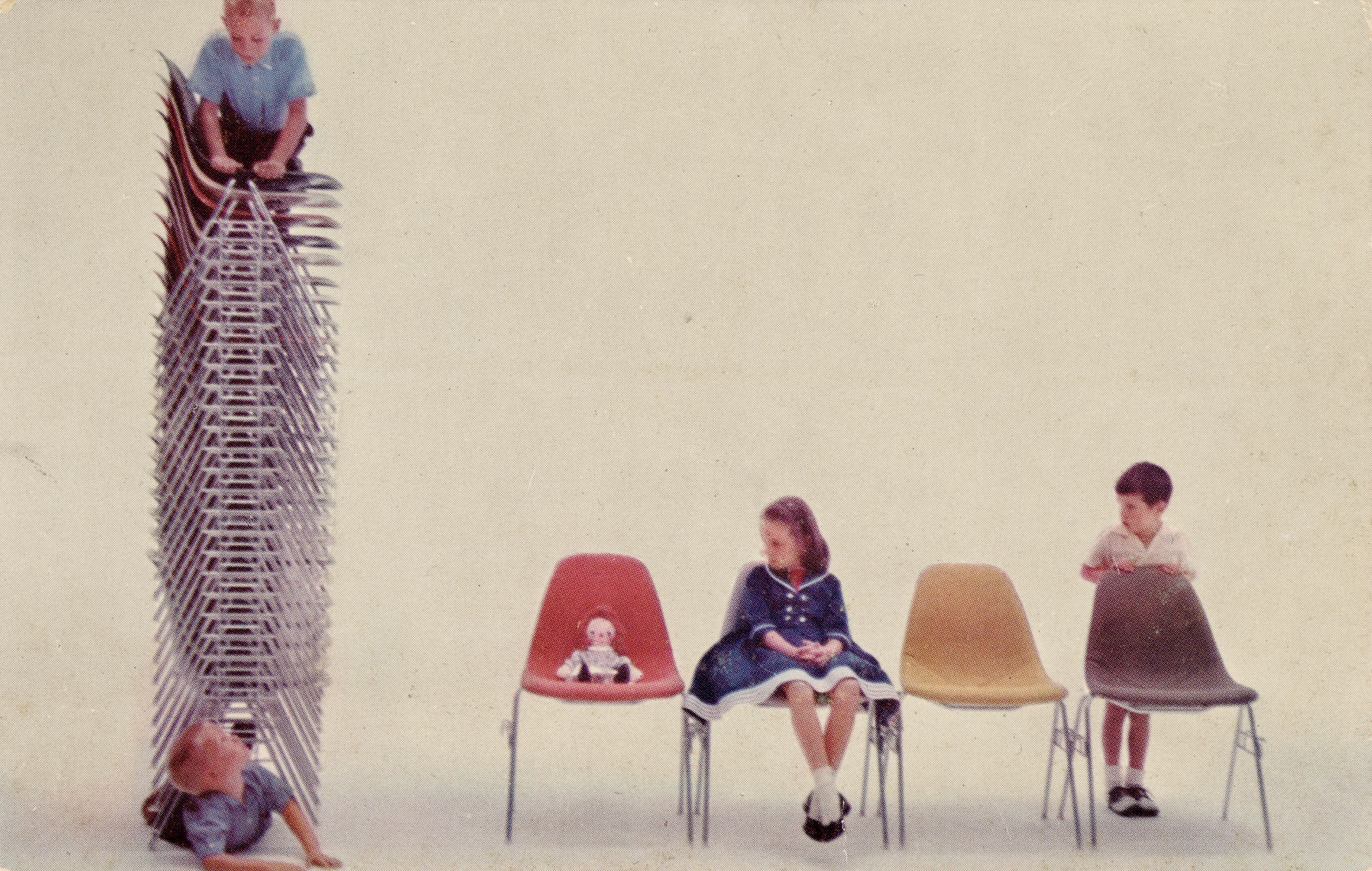 Herman Miller postcard with several children among Eames DSS chairs side by side and a tall stack of DSS chairs on the left.