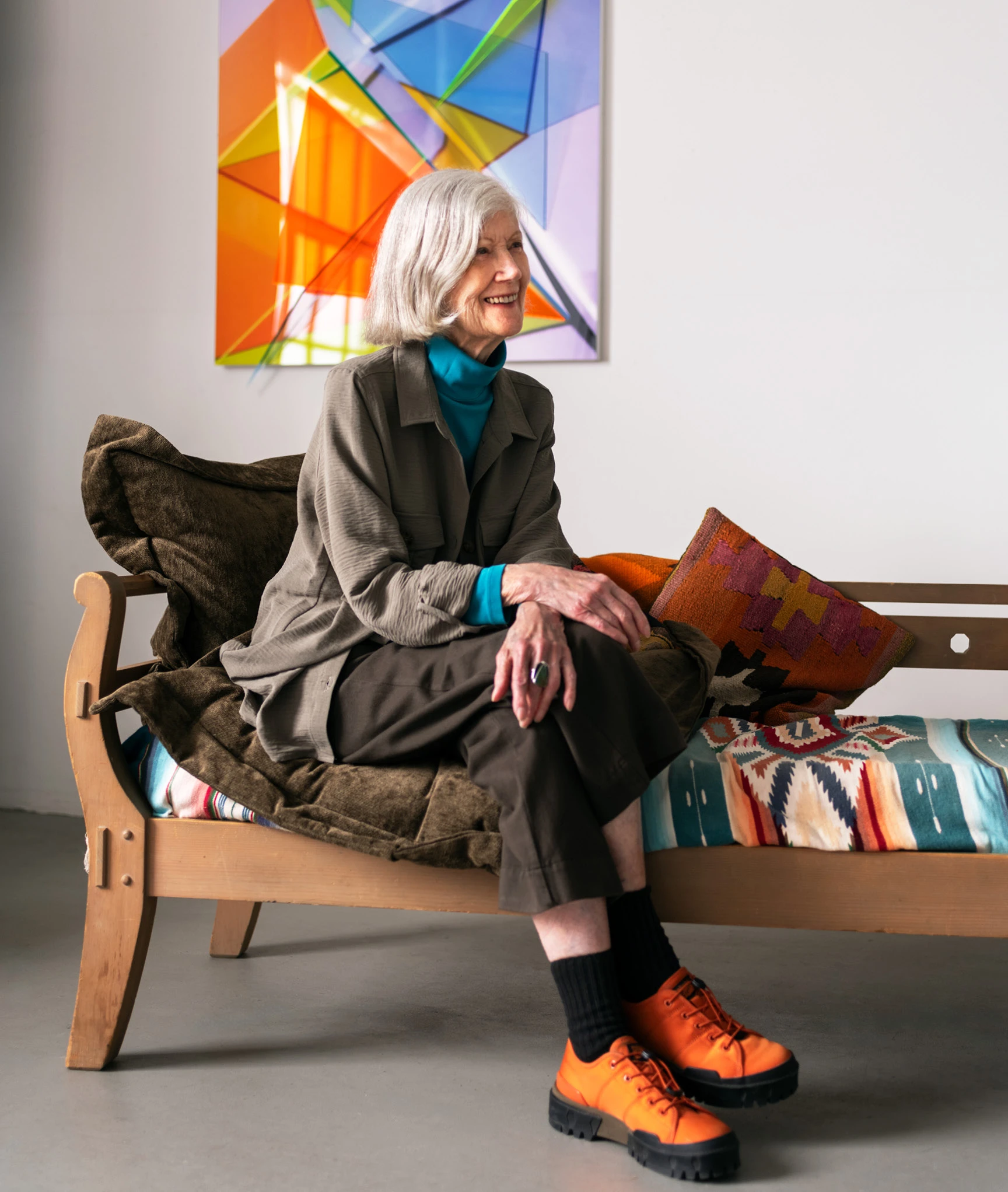 Chicago artist Barbara Kasten seated on a colorful daybed with her piece, Progression Seven, in the background.