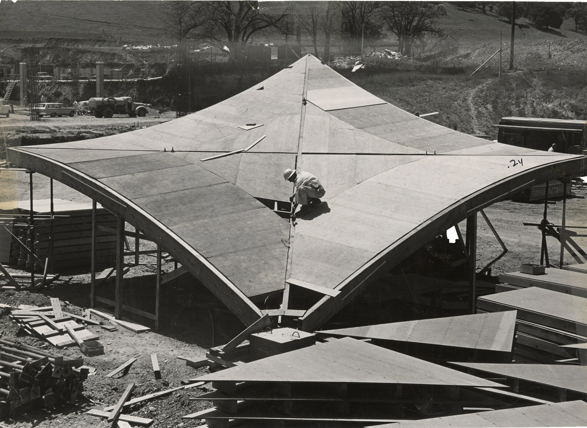 Front view of a worker applying plywood sheathing to the hyperbolic paraboloid form for the concrete roof by John S. Bolles.