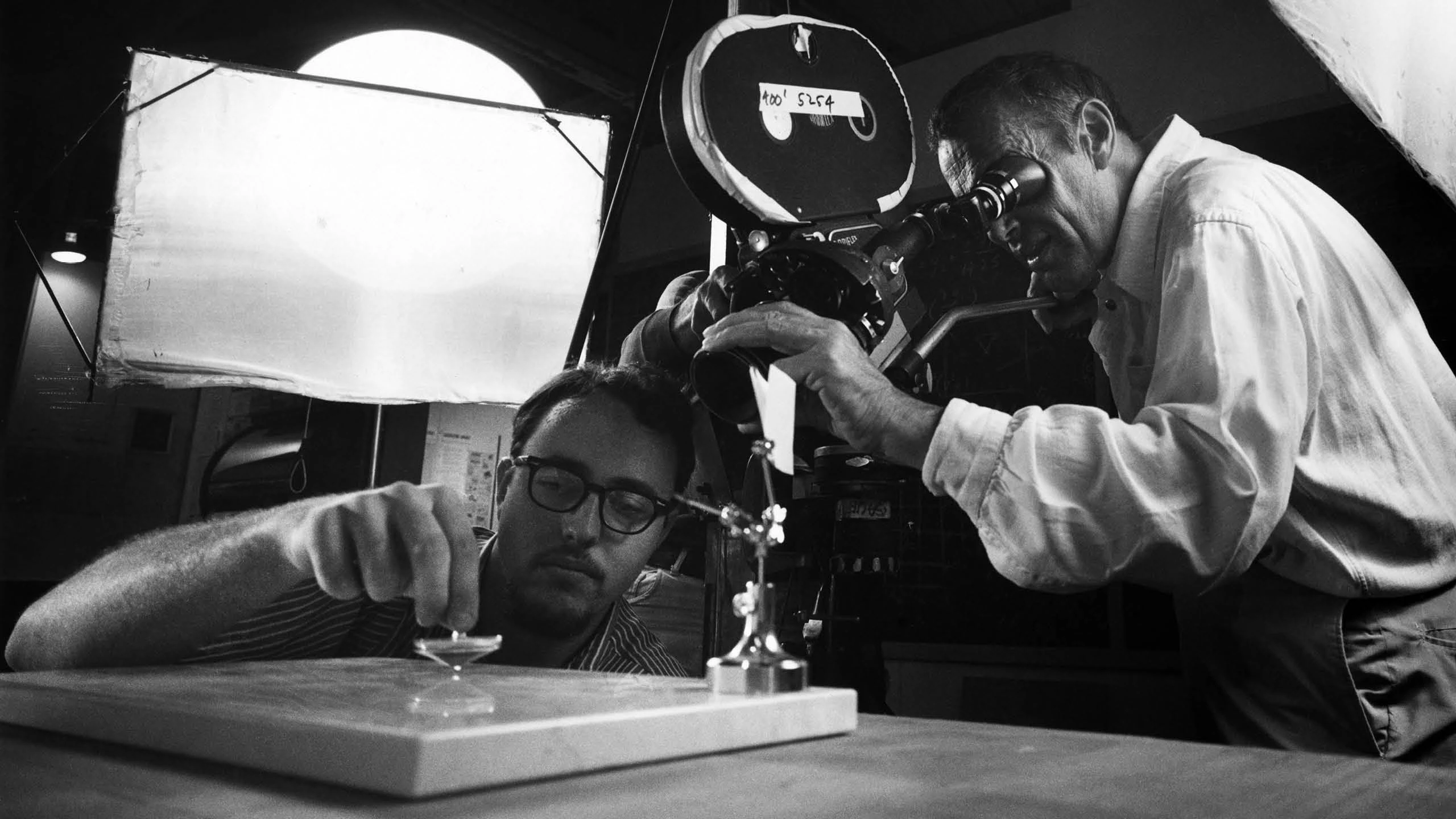 Charles Eames and staff member Alex Funke are shown capturing one of the 123 featured tops in motion for the film Tops.