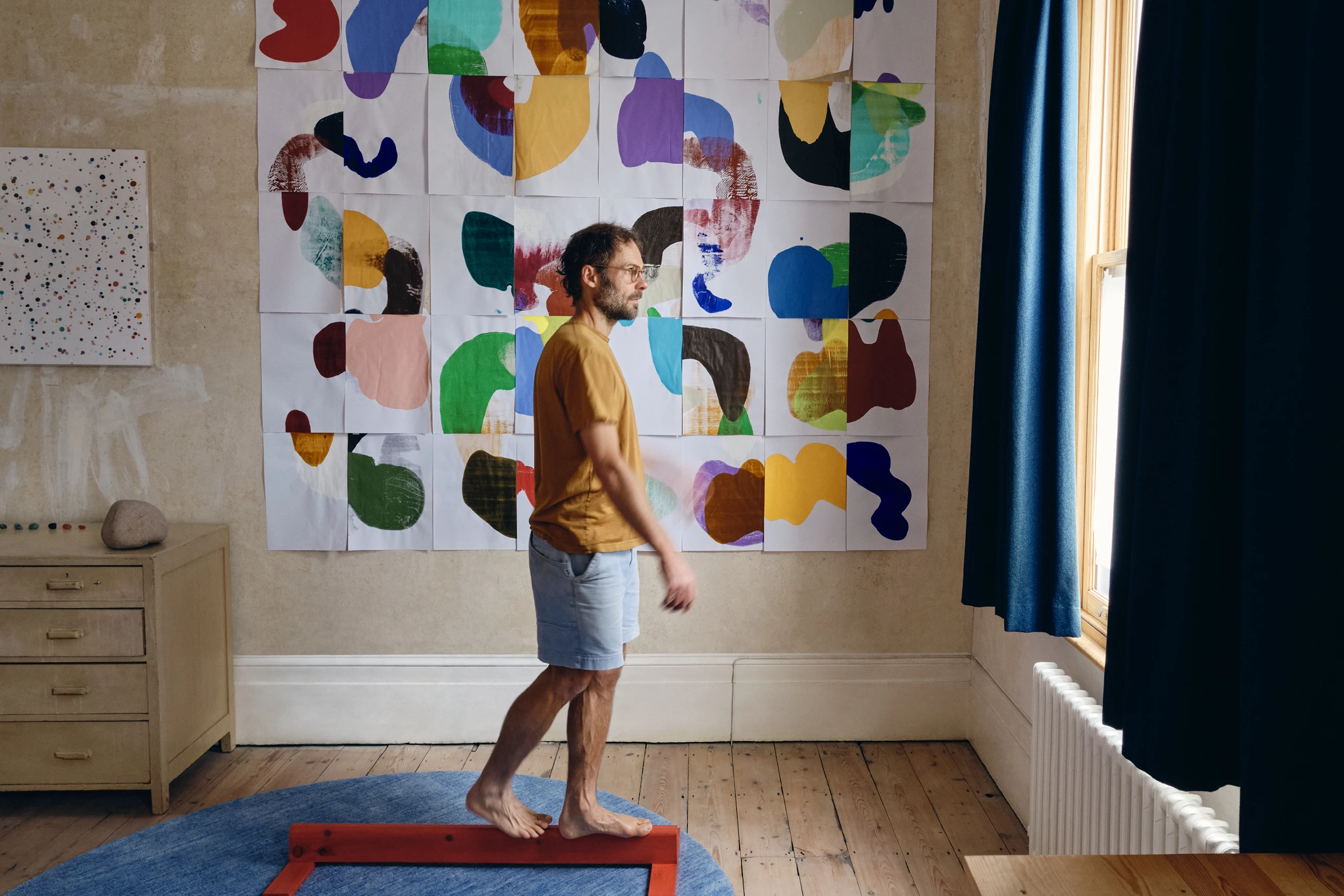 Artist Daniel Eatock in his London art studio with a wall of assembled roll forms from his rolling pin paintings.