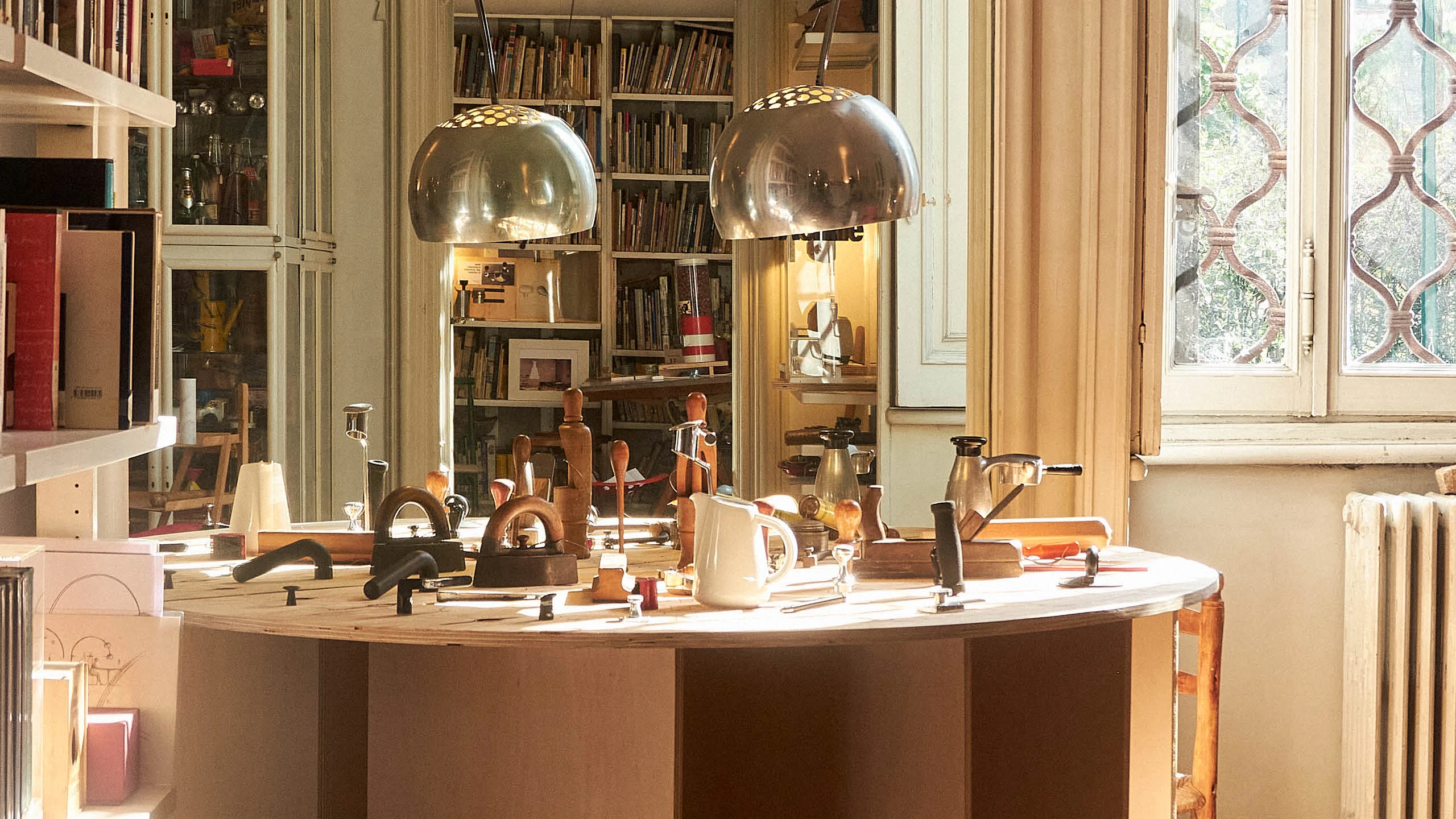 A table in Achille Castiglioni’s Milan studio filled with prototypes and reference materials reflecting his design process.