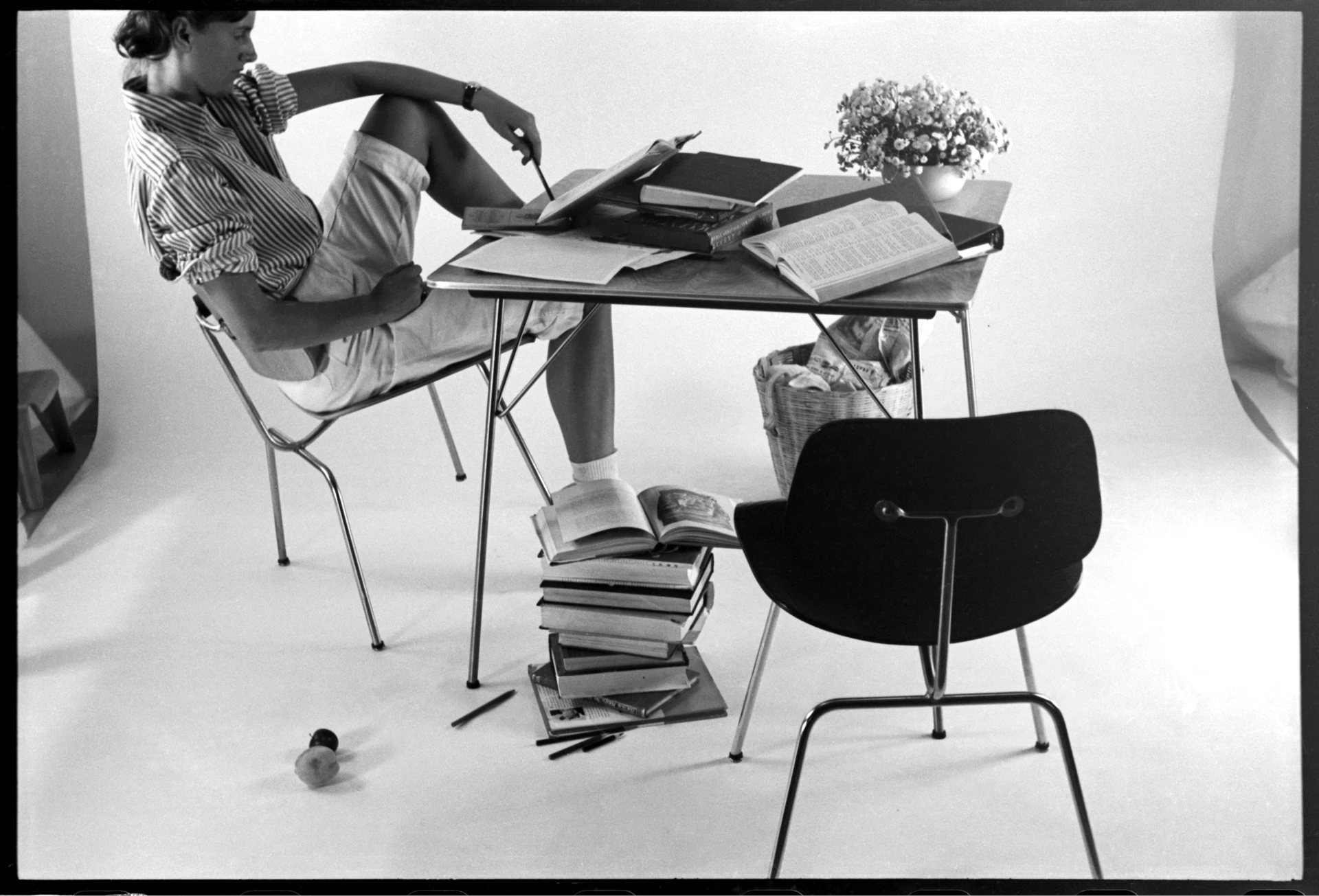 A young Lucia Eames models one potential use for the folding DTM (Dining Table Metal). © Eames Office, LLC
