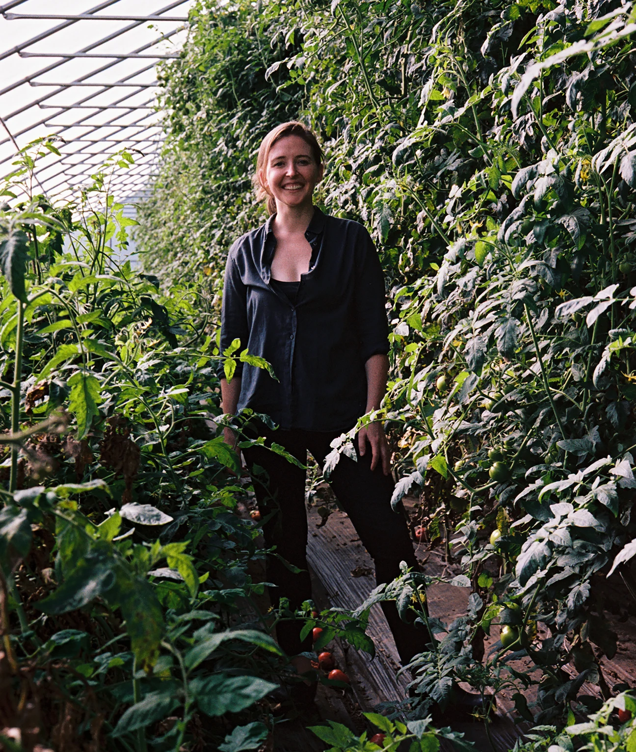 MASS Design Group's Caitlin Taylor surrounded by many large plantings at Four Root Farm in East Haddam, Connecticut.