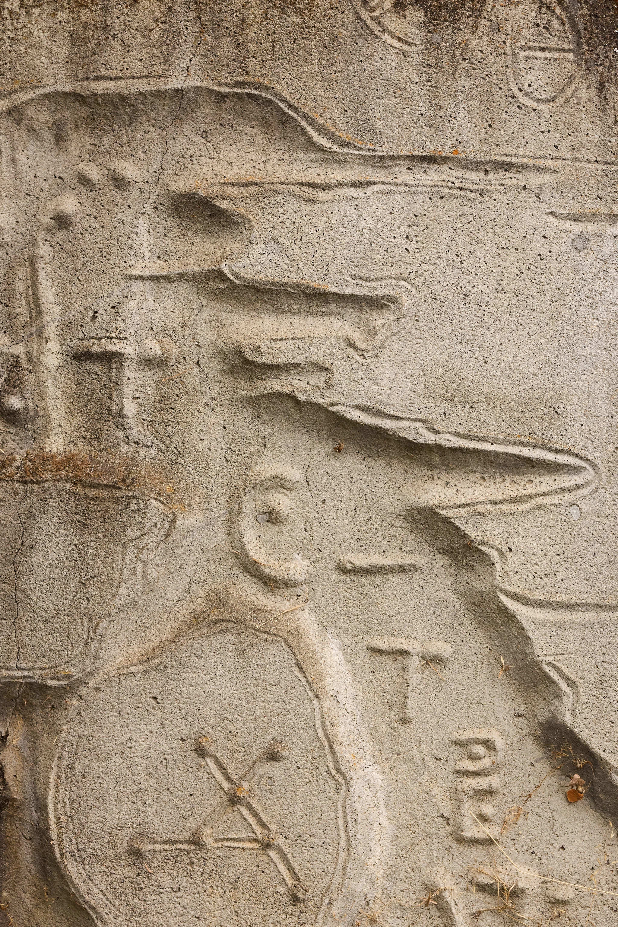 Close up from a carved concrete relief mural by artist Gurdon Woods featuring mathematical like symbolic marks.