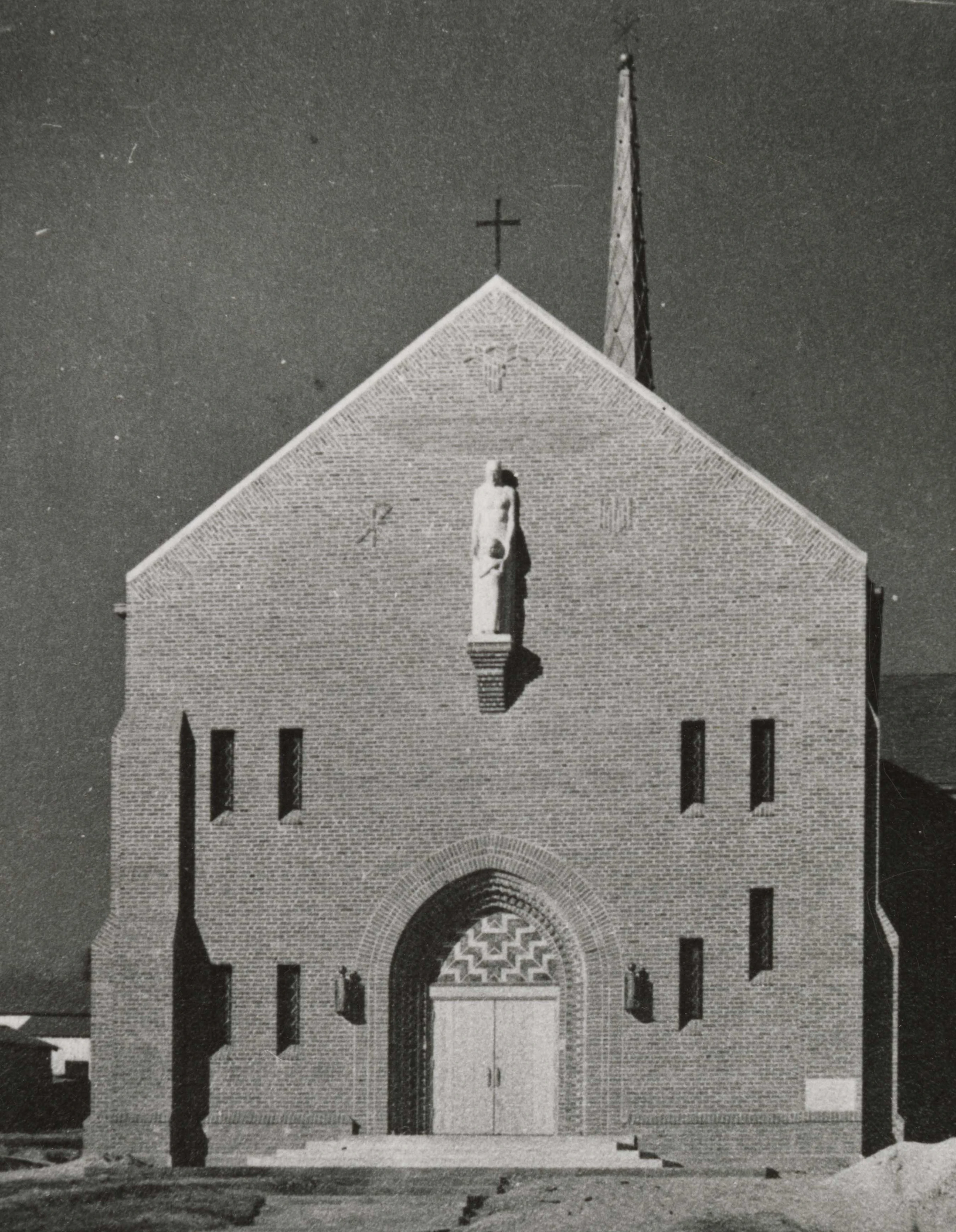 Front view of St. Mary’s Church designed by Charles Eames with several slender stained glass windows and an arched doorway.