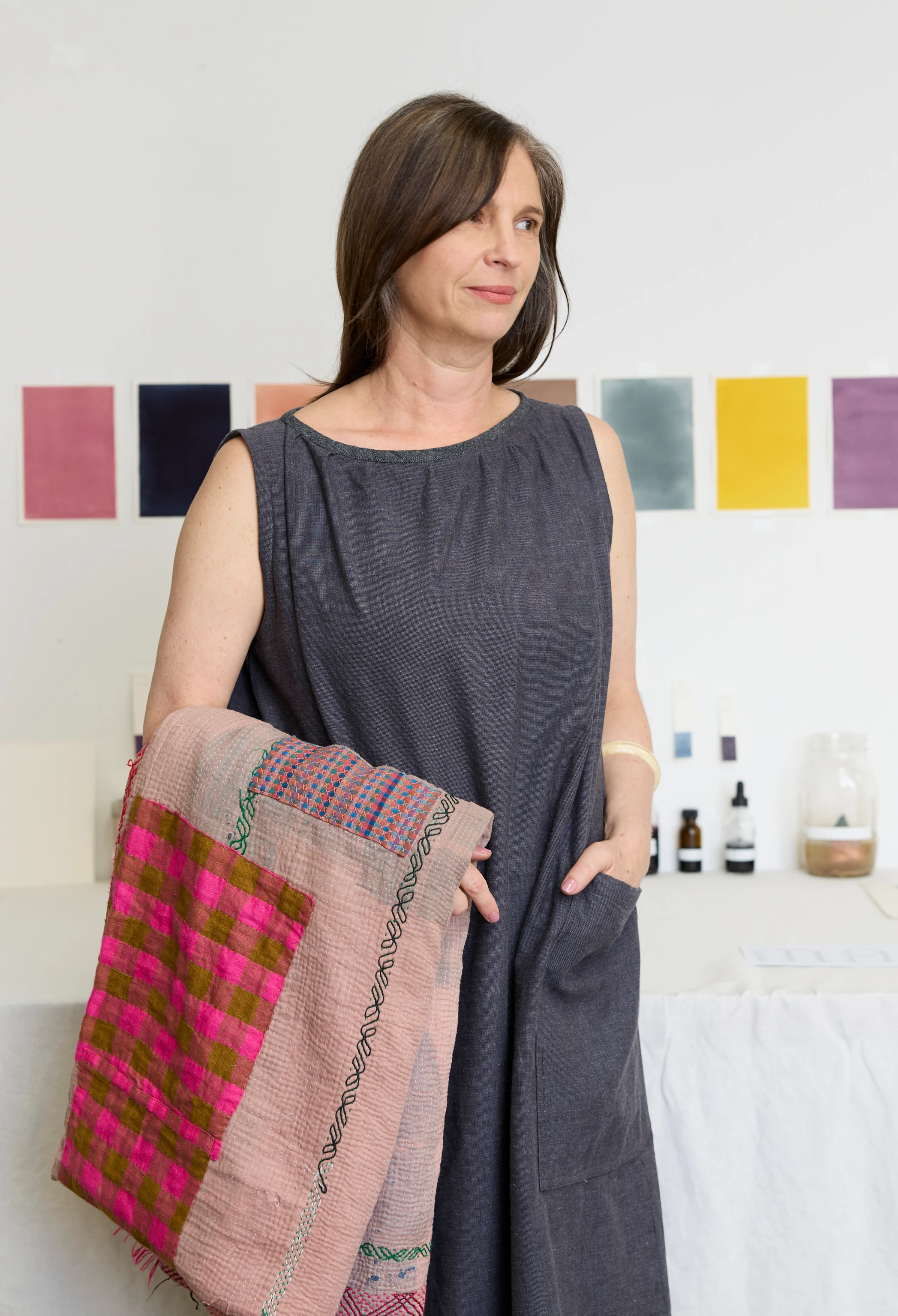Artist Lena Wolff holding a colorful quilt.