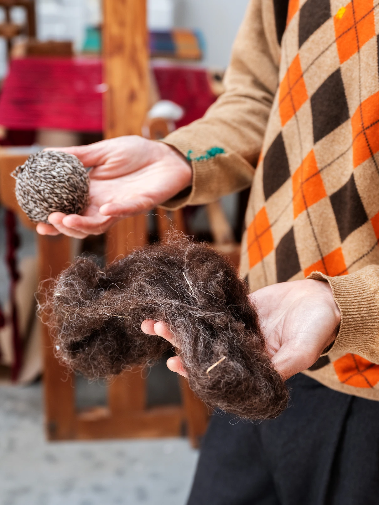 Close up of raw wool and wool yarn being held in two hands.