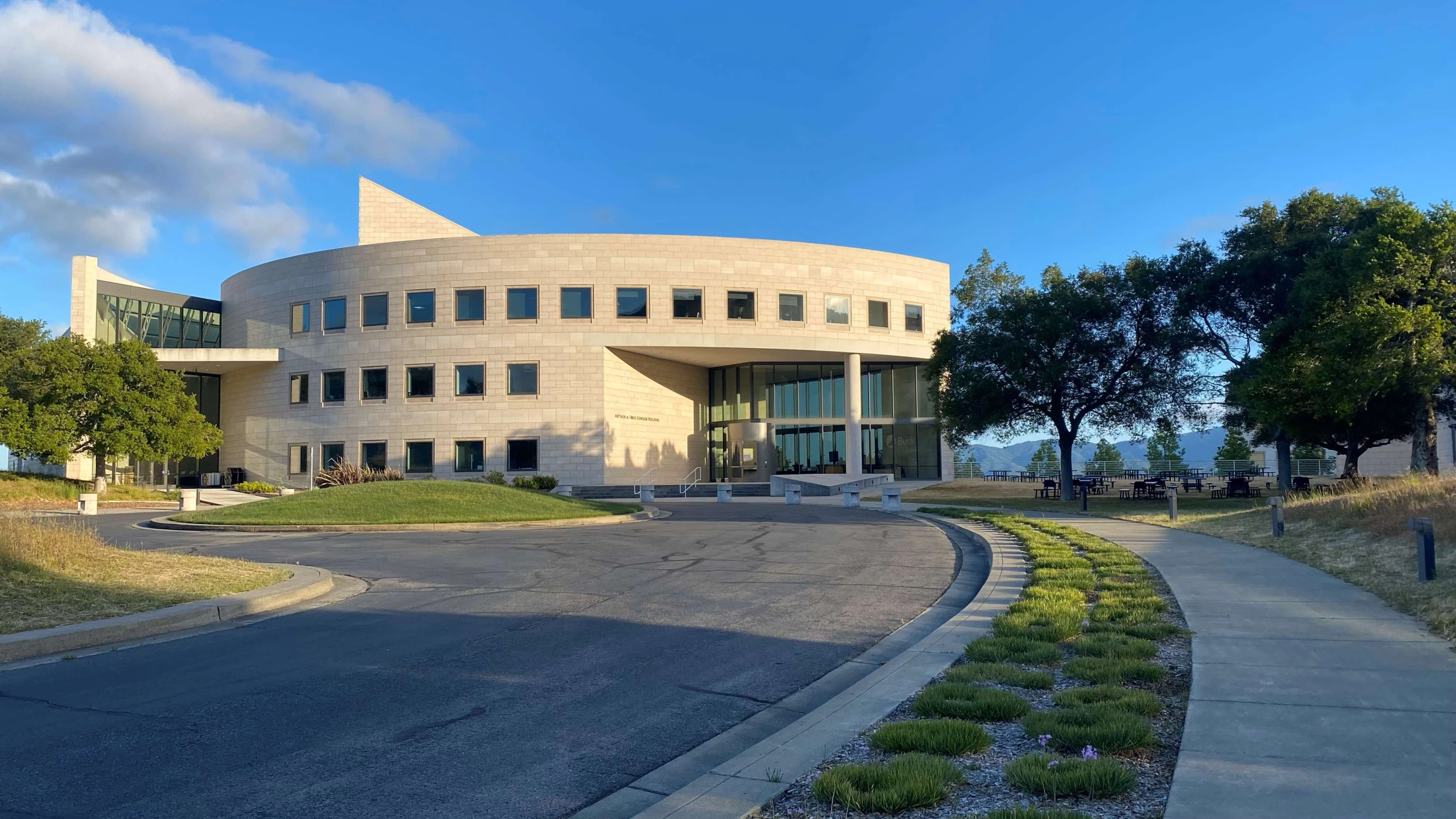 Exterior of the Buck Institute's I. M. Pei–designed building, featuring a curved concrete façade, square windows, and a glass entrance.