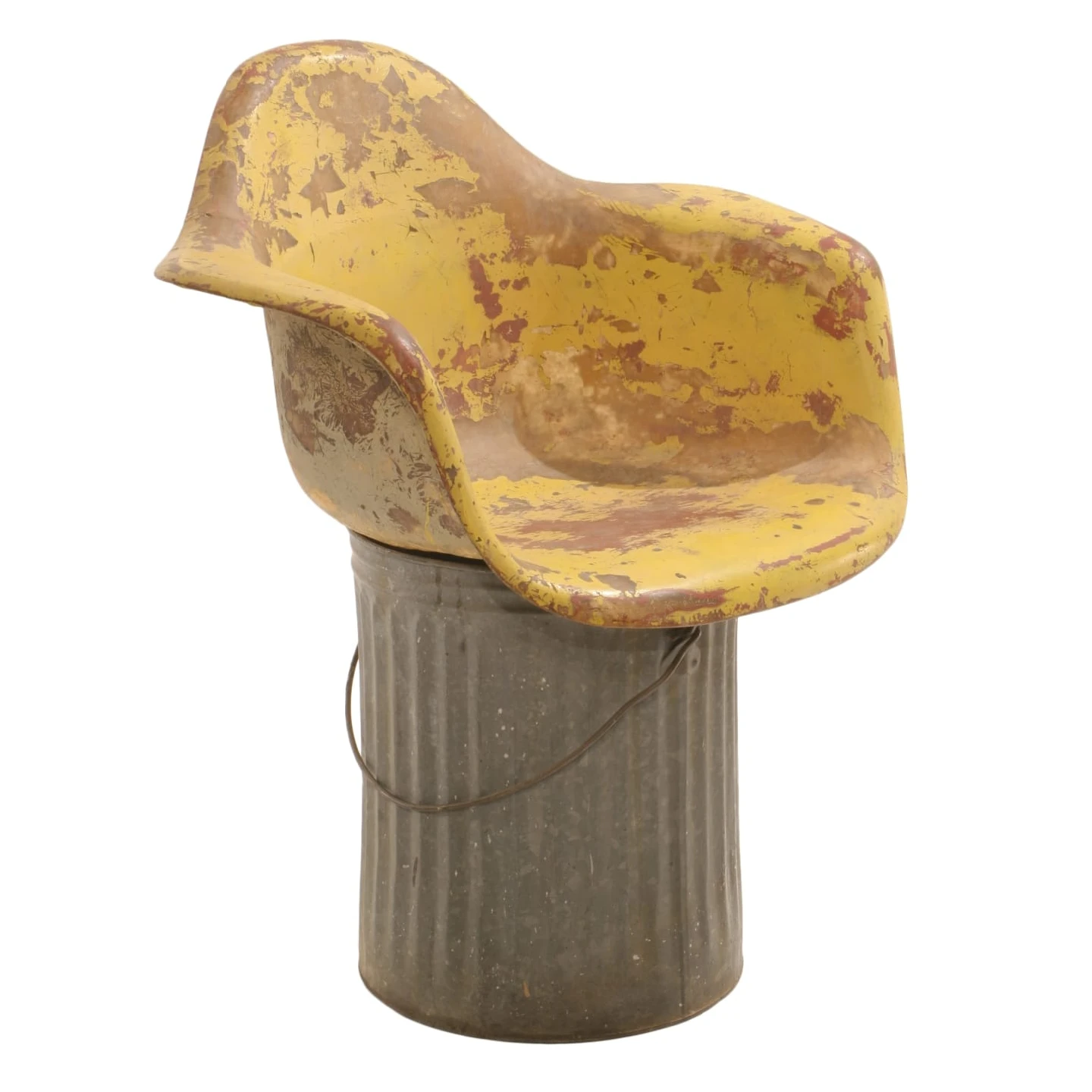 Side view of the Eames Fiberglass Chair prototype in yellow with orange marks, resting on a metal drum.