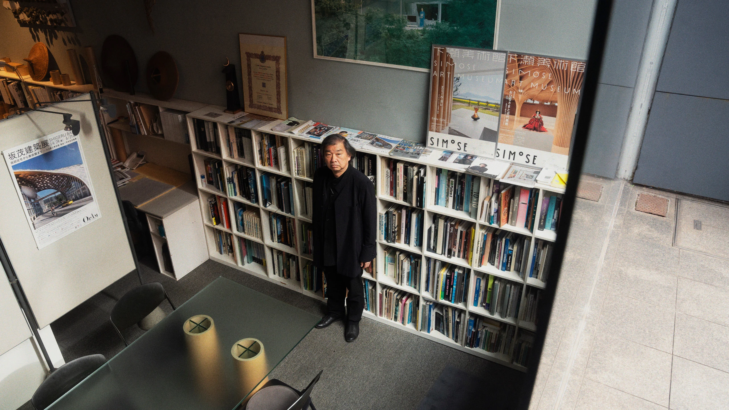 Architect Shigeru Ban standing in front of bookcases inside the office of Shigeru Ban Architects.