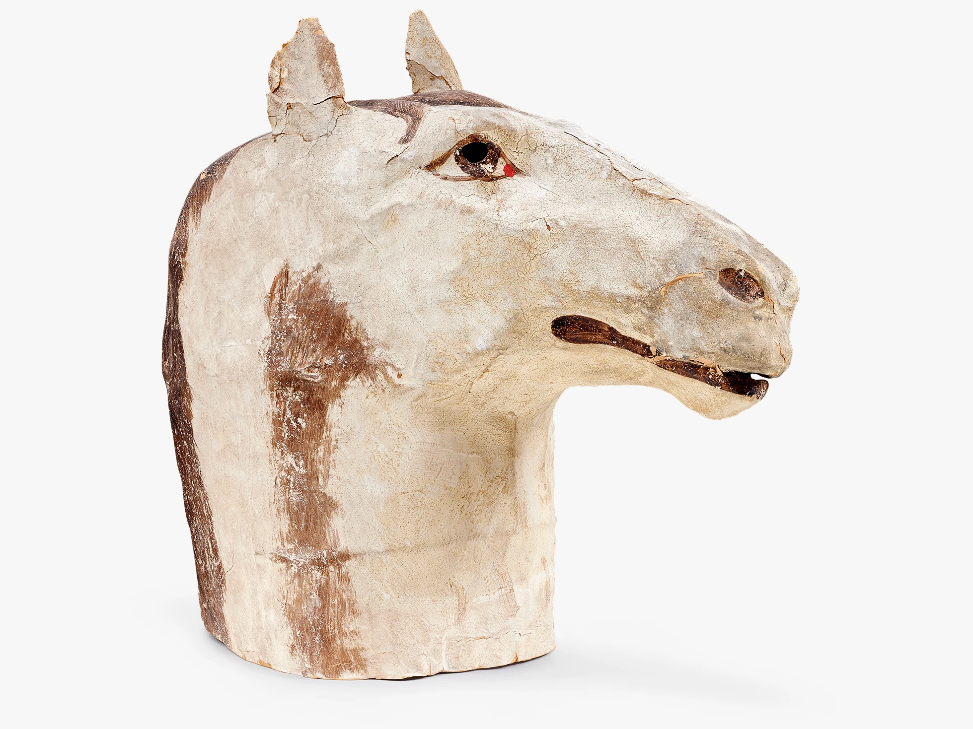 Side view of a white papier-mache horse head mask that is painted white and brown.