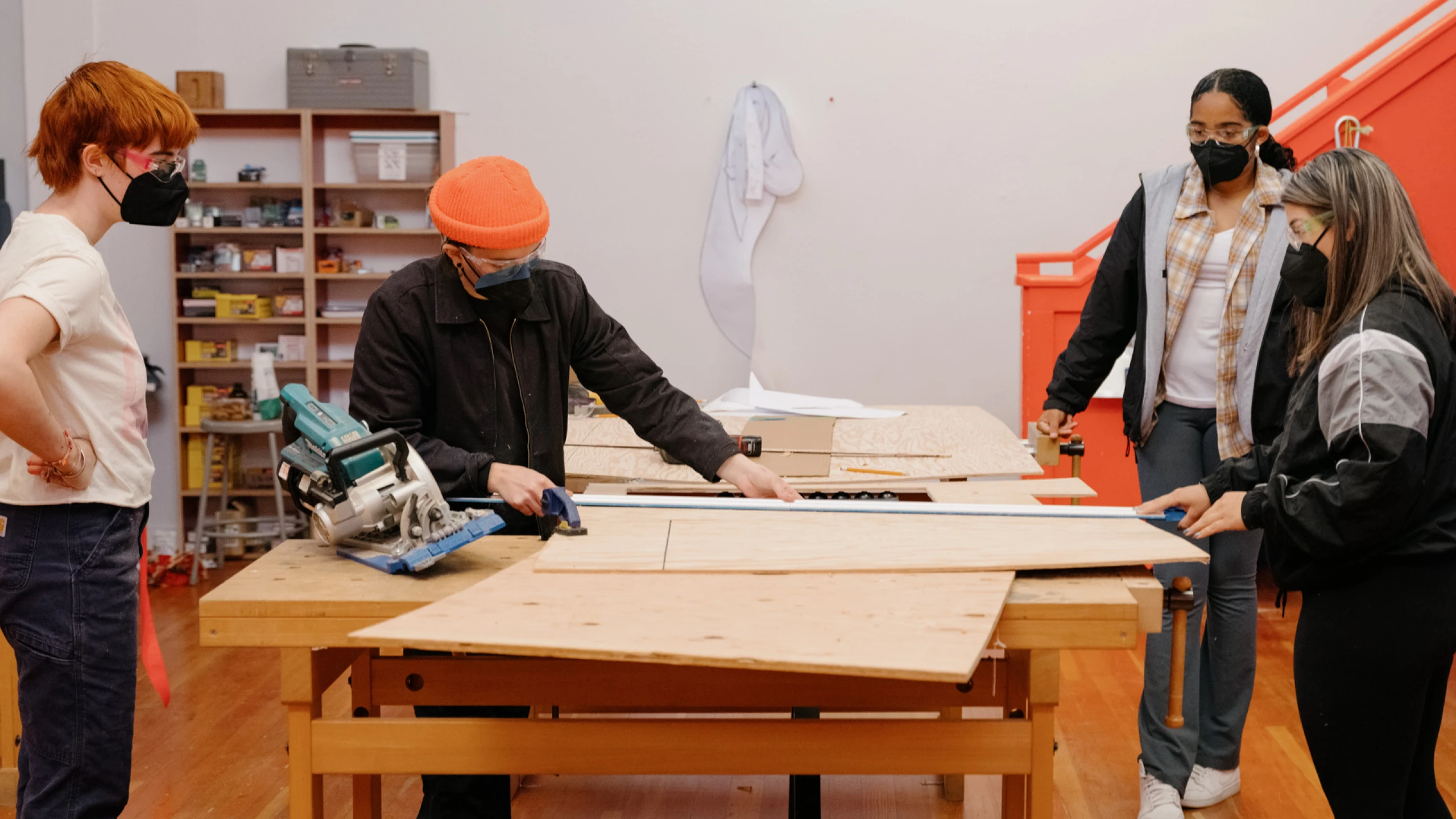 Girls Garage, a workshop and design/build program in Berkeley California, showing several students around a worktable.