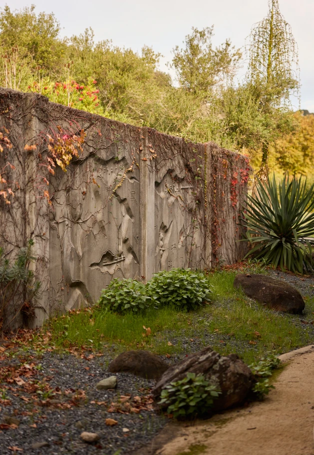 Angled view of a concrete relief mural by artist Gurdon Woods with trees in the background.
