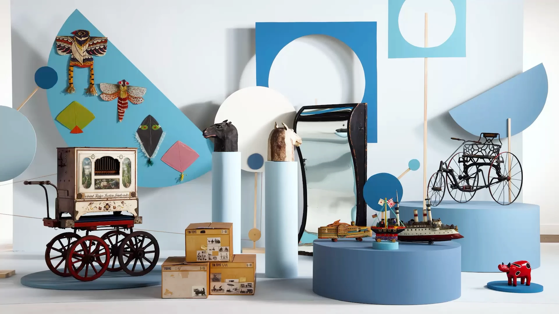 Various toys collected by the Eameses sitting on risers in many shades of blue.