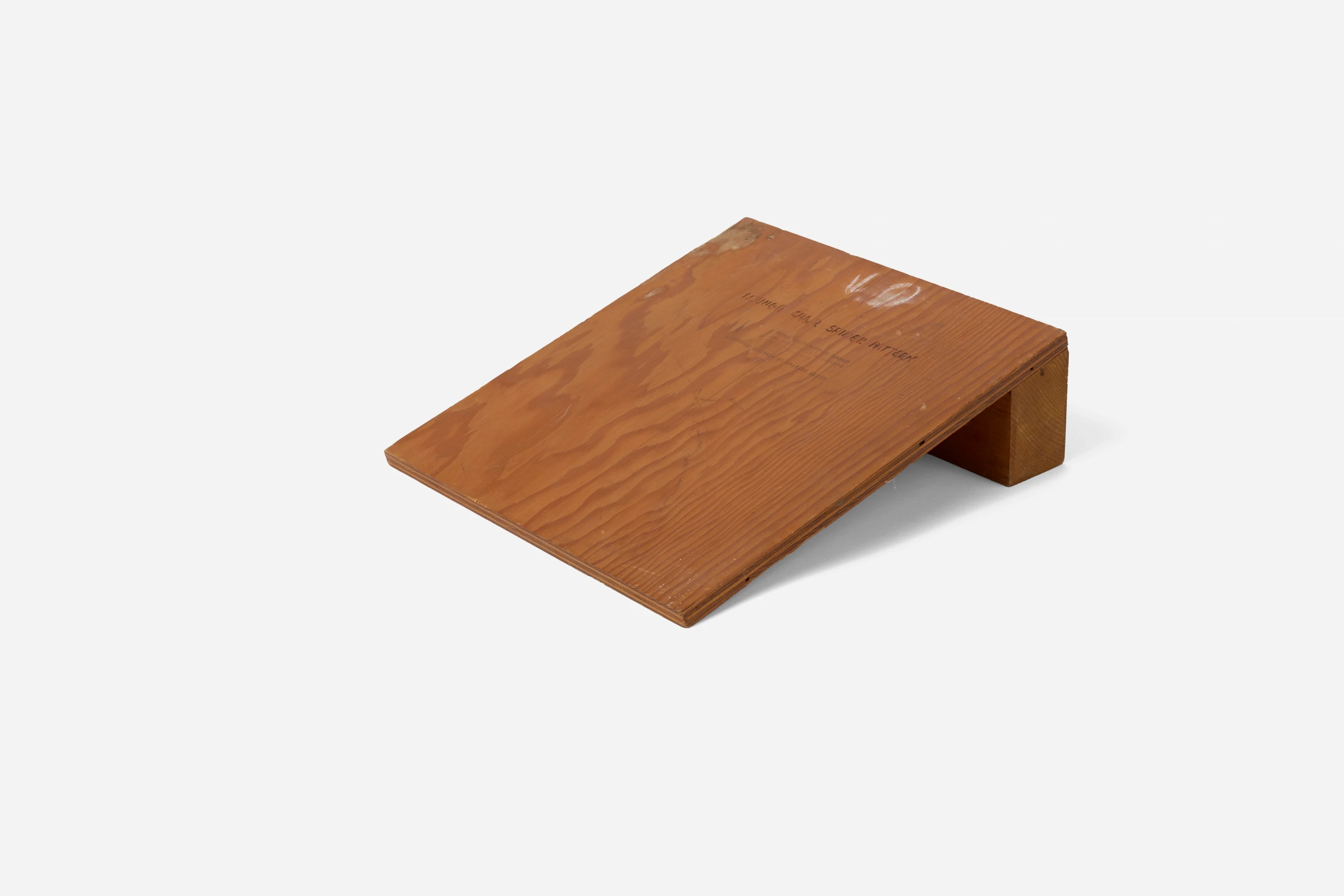 Three quarter side view of an angled wooden plank that was used to display the Eames Lounge Chair three point spider or base.