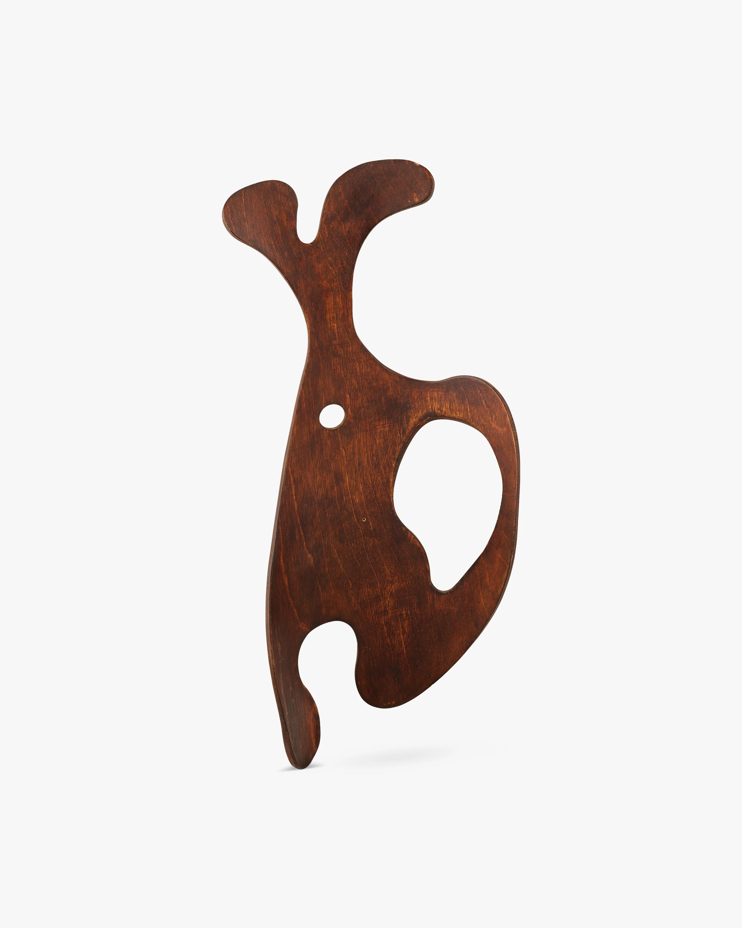 Front view of a sculpture designed by Ray Eames cut from a mahogany splint and stained brown.