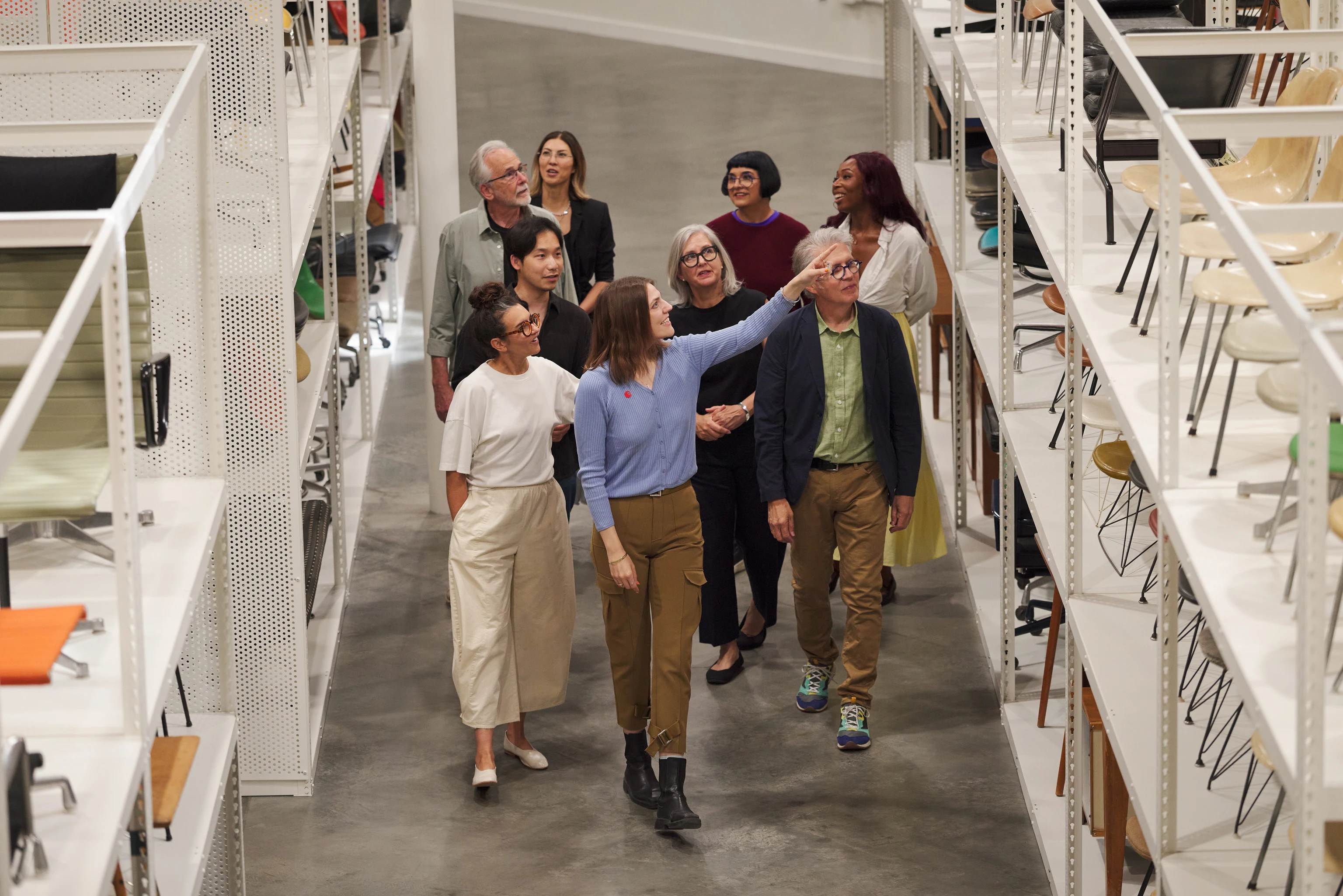 A guided tour of the Eames Institute archives among shelves filled with furniture and objects from the Eames collection.