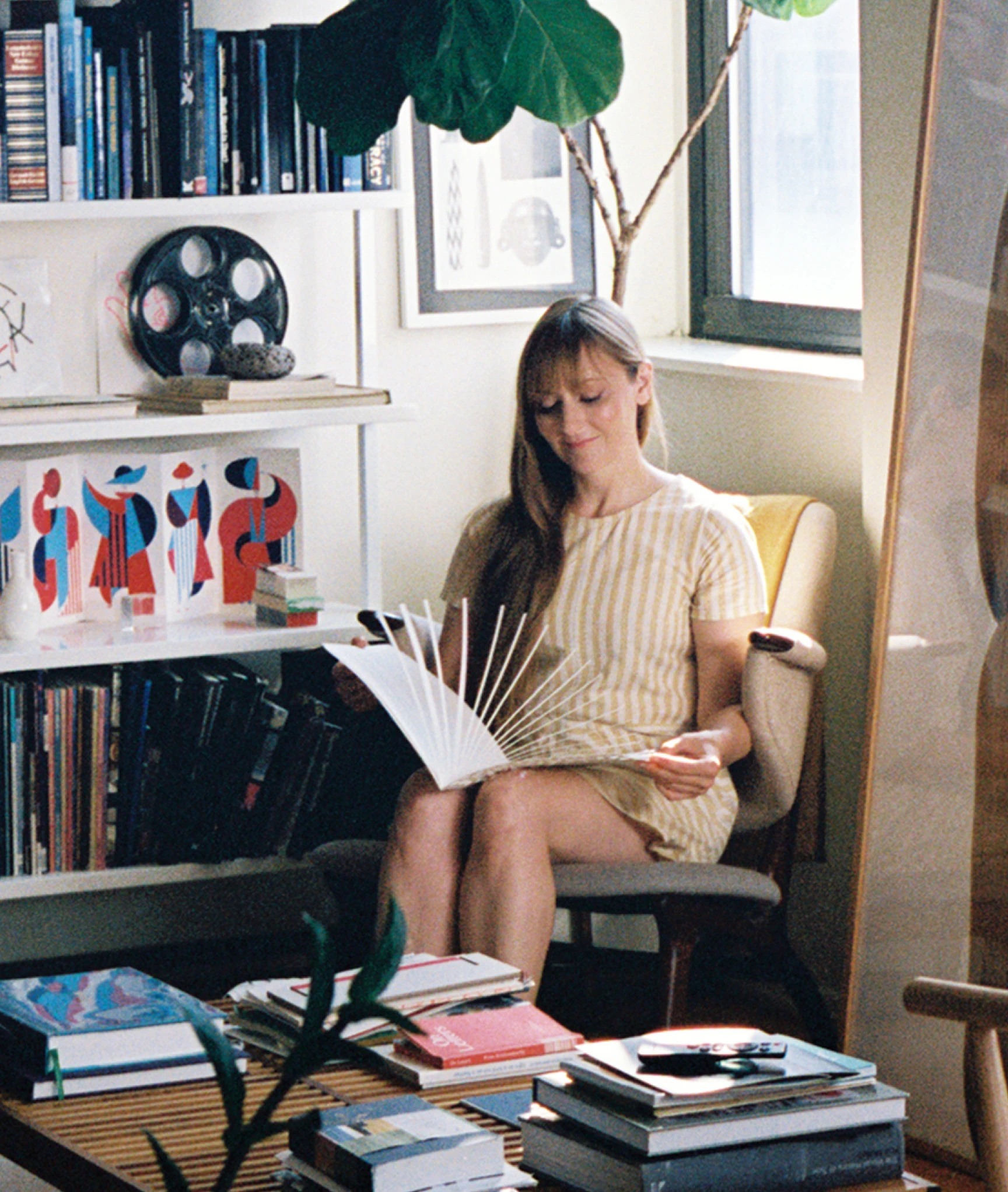 Designer and paper engineer, Kelli Anderson, in her studio browsing one of her books.