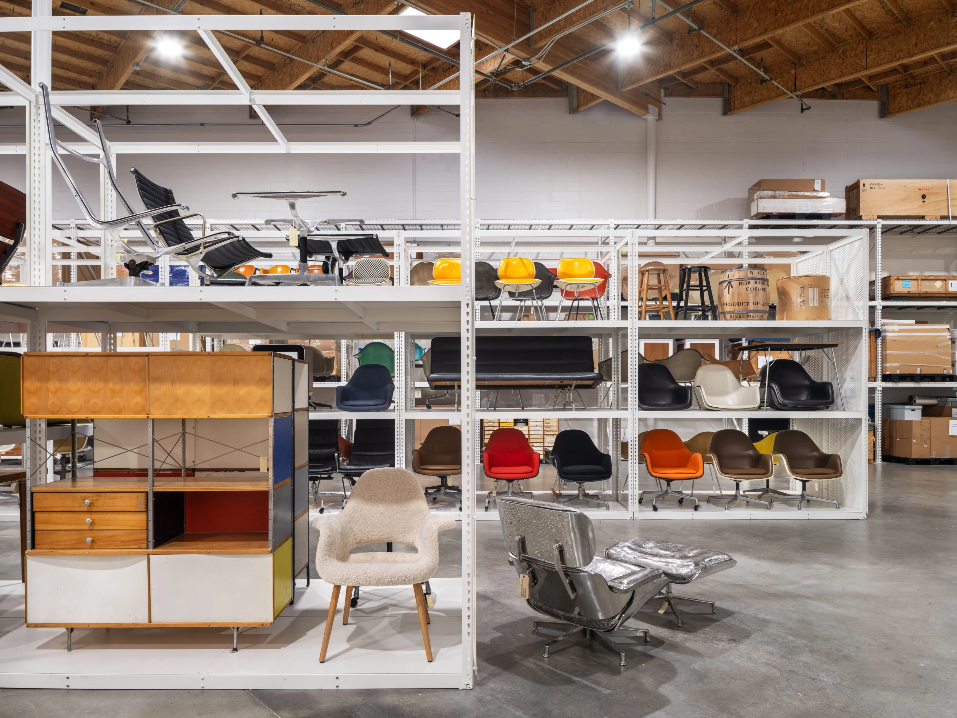 Interior view of the Eames Archives featuring white shelves filled with Eames furniture.