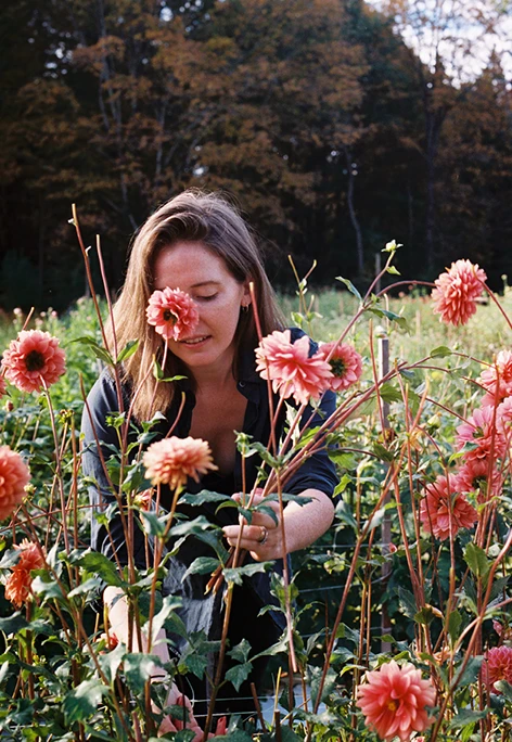 MASS Design Group's Caitlin Taylor tending to pink flowers at Four Root Farm in East Haddam, Connecticut.
