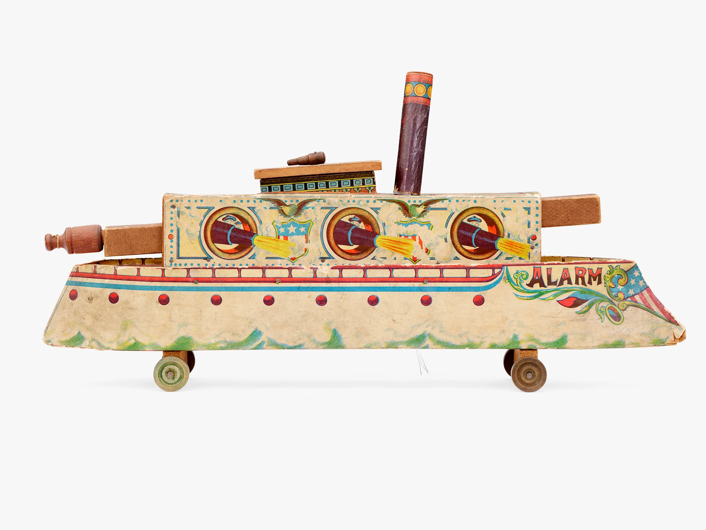 Side view of a colorful toy boat made of wood, paper, and metal with the word “Alarm” in red at the boat’s bow.