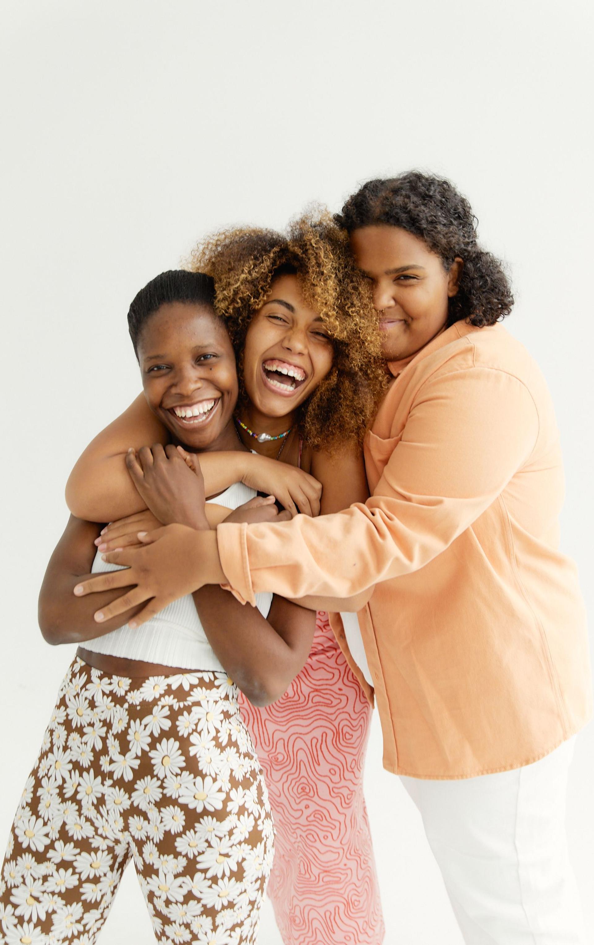 Three smiling women standing together outdoors