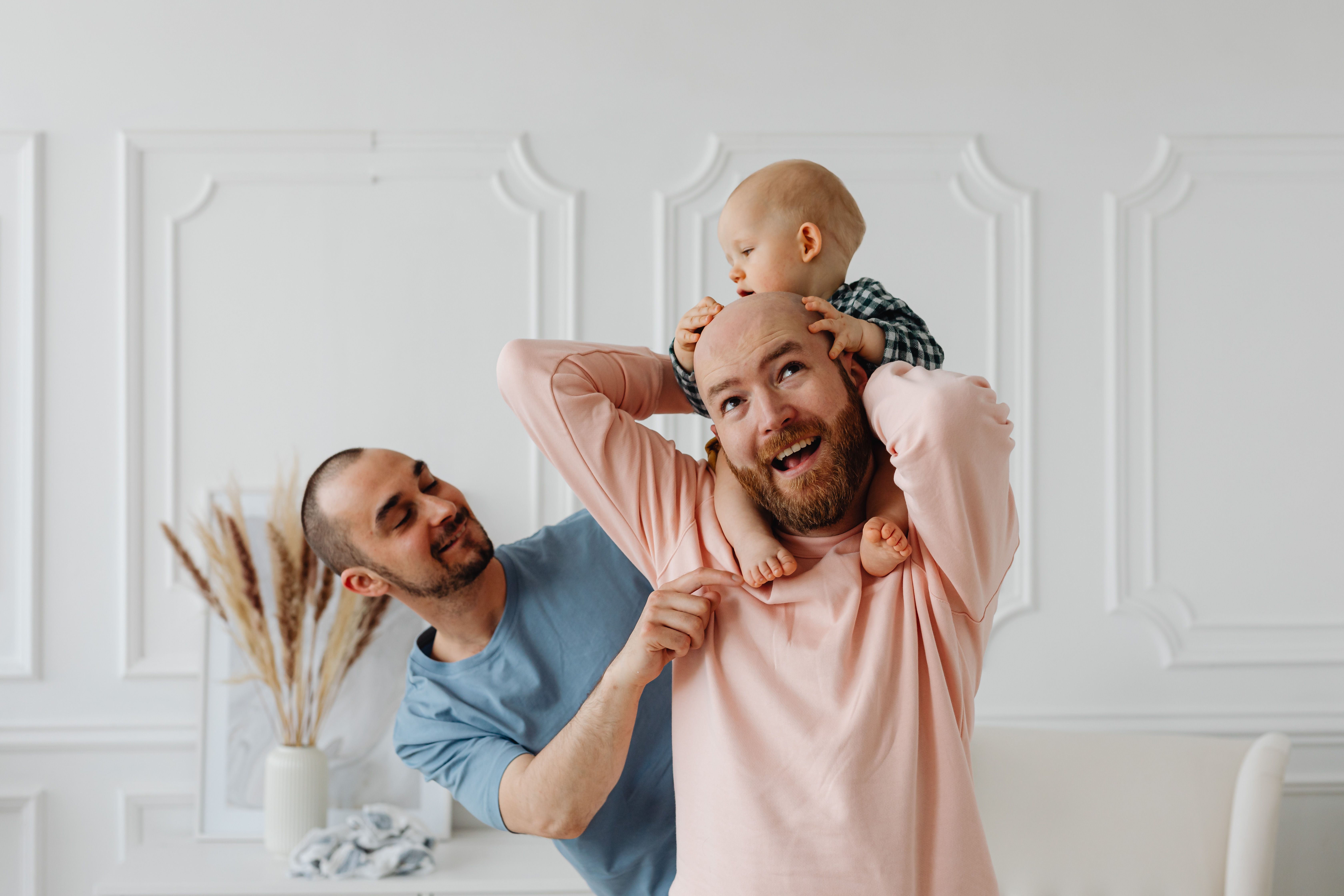 two men as a family holding a baby