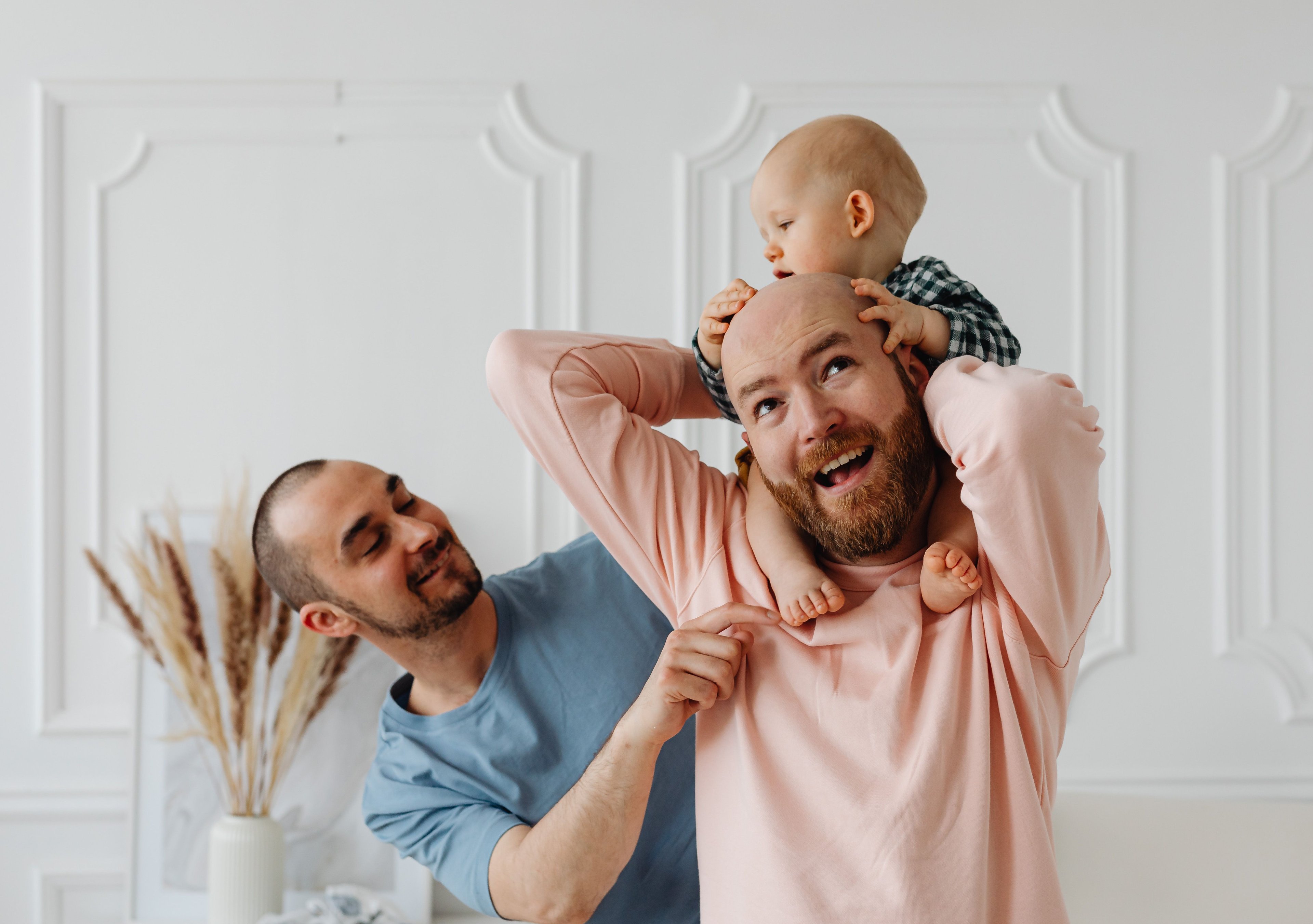 two men as a family holding a baby