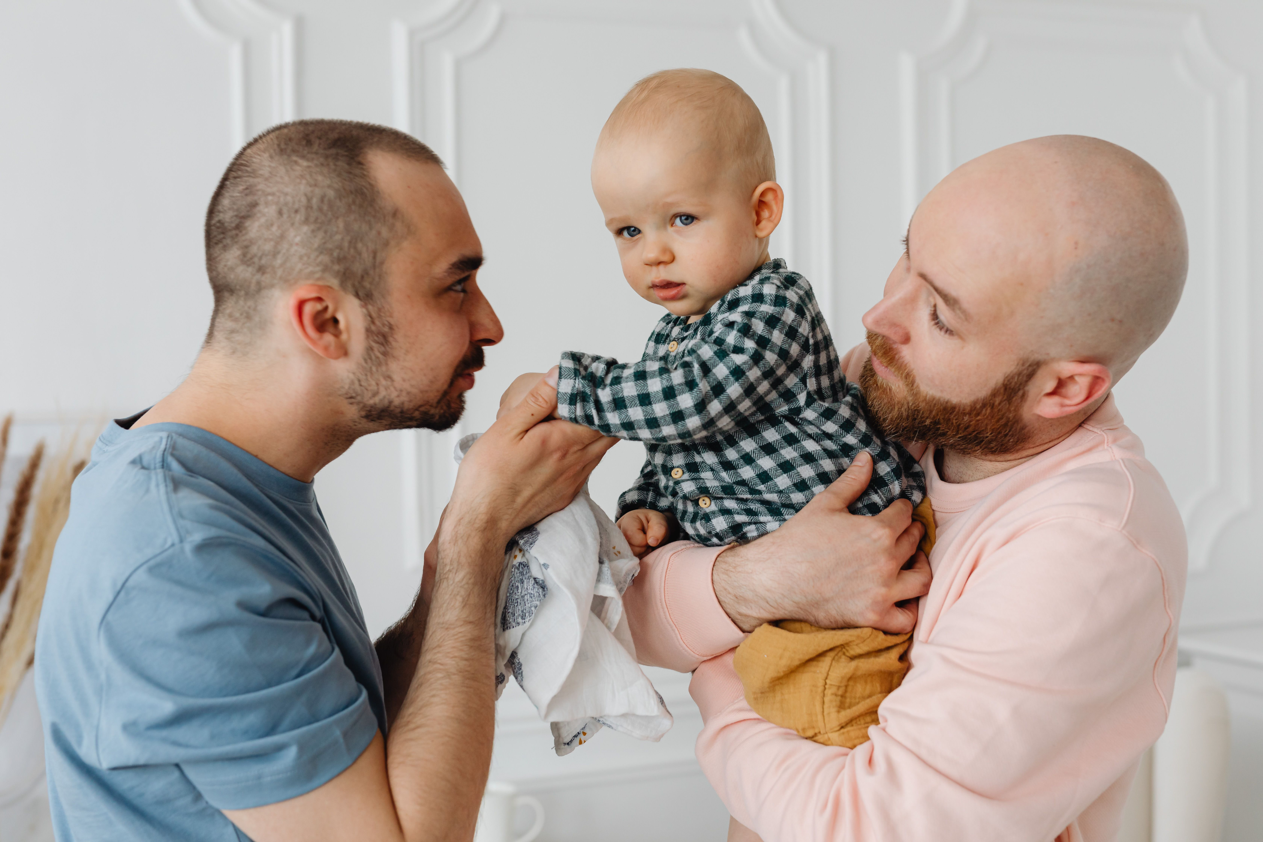 Two fathers holding their baby