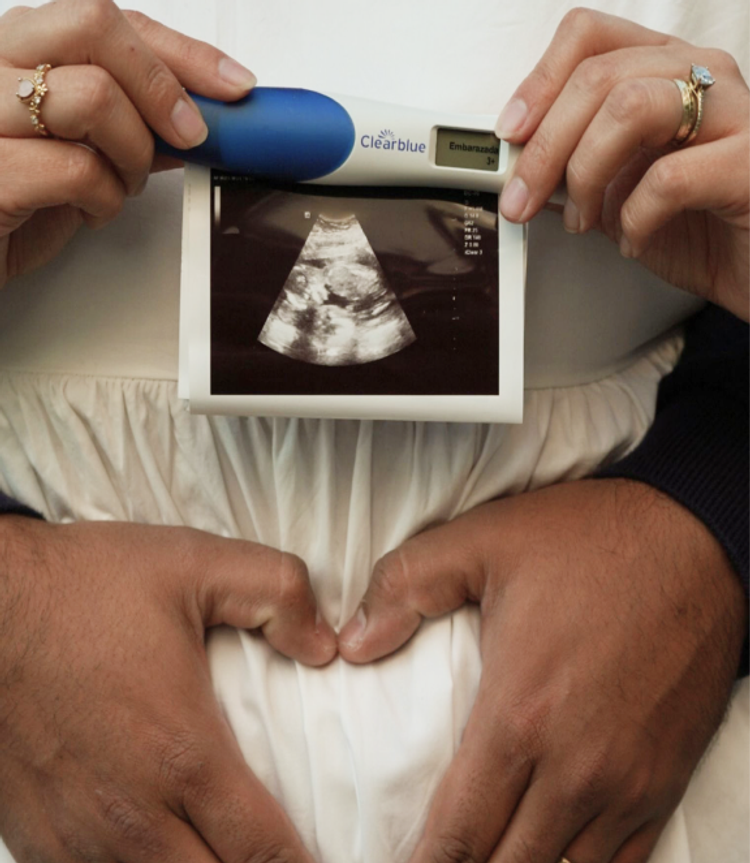 Hands holding a sonogram and pregnancy test