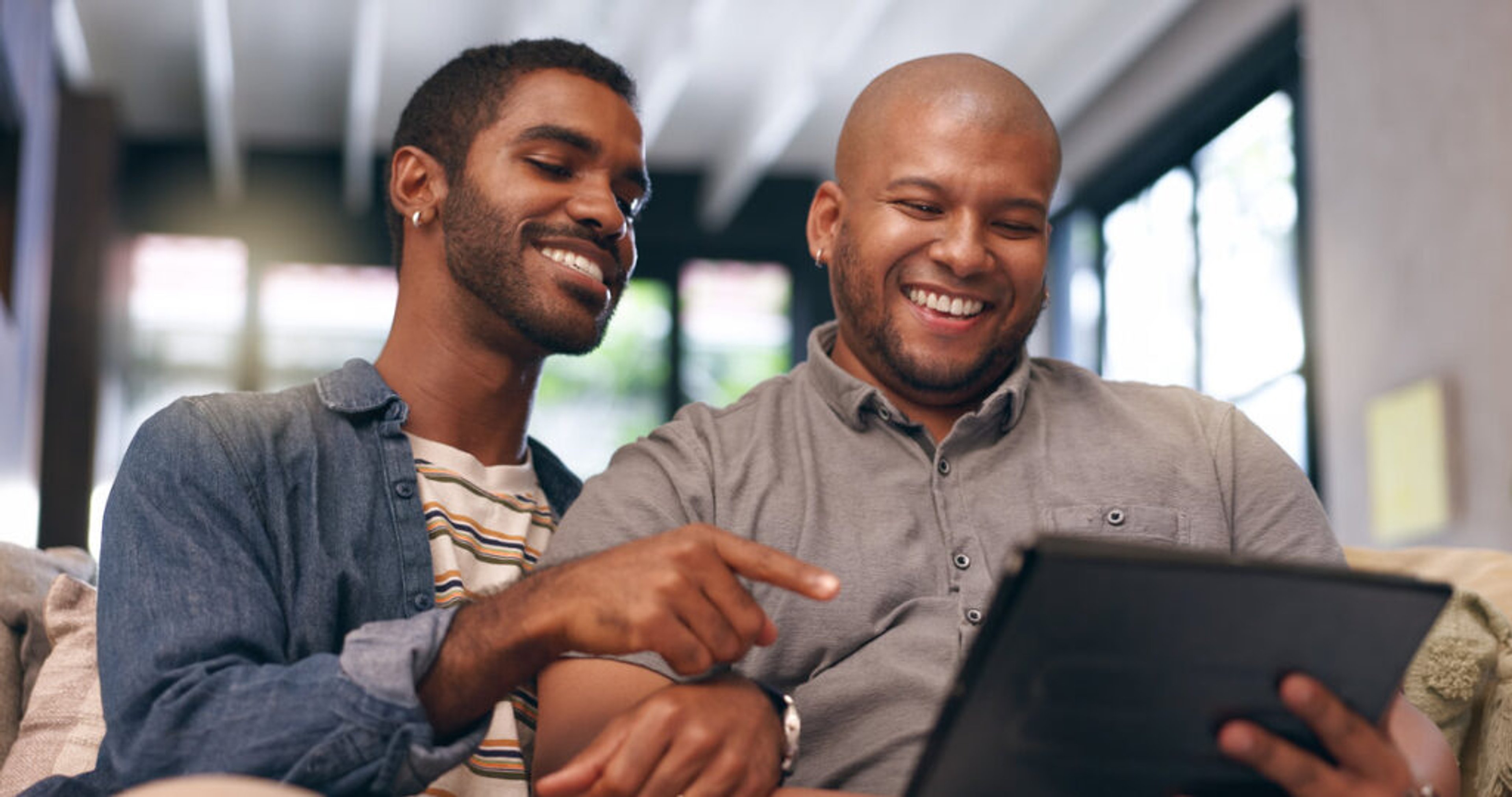 House, gay couple or men with tablet, love or smile for renovation blog research in living room. Choice, lgbtq or happy people on technology together in home with queer partner for interior design.