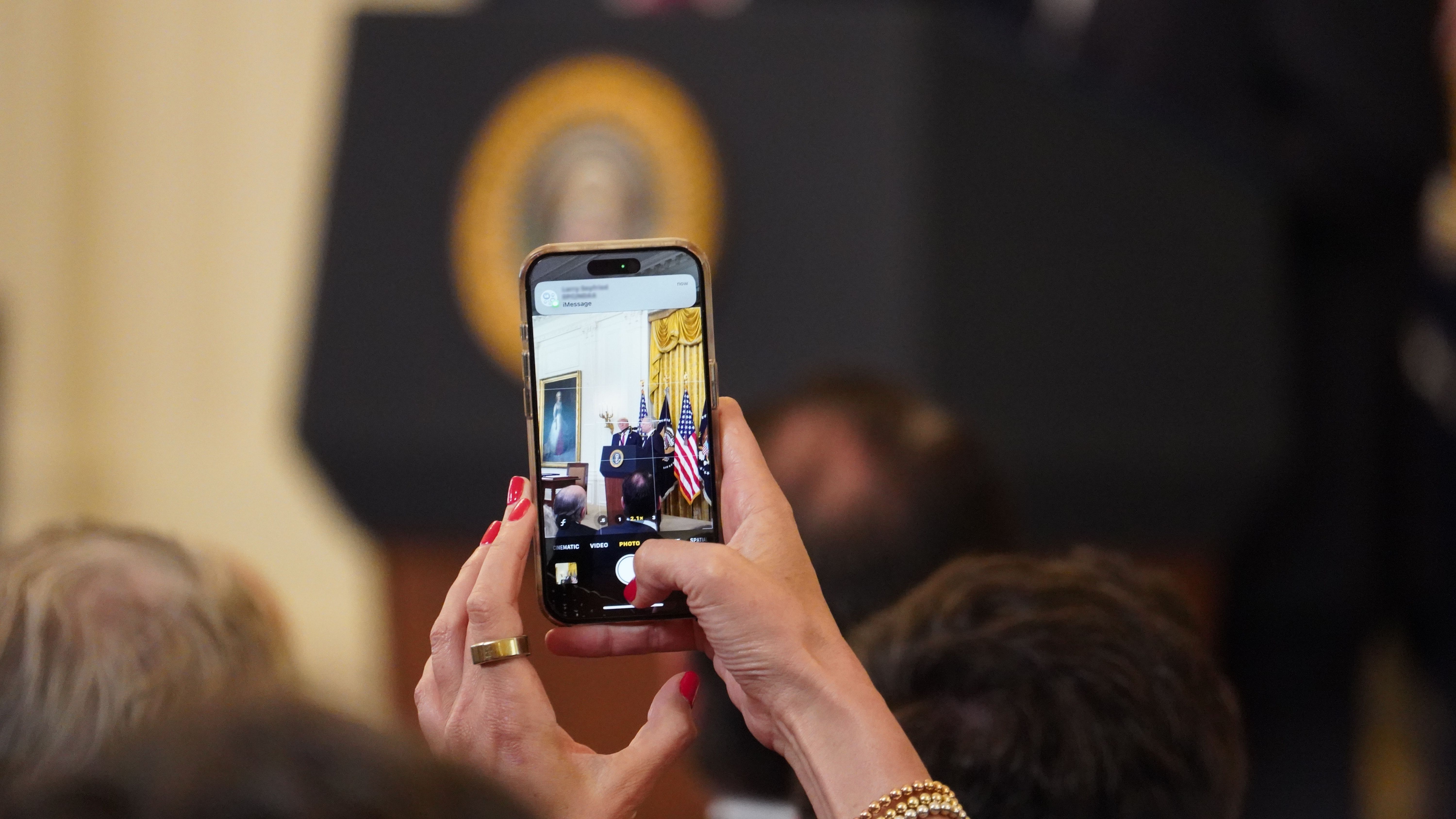 An attendee takes a photo of Donald Trump speaking ahead of the GENIUS Act signing in the White House on July 18, 2025. (Nikhilesh De/CoinDesk) An attendee takes a photo of Donald Trump speaking ahead of the GENIUS Act signing in the White House on July 18, 2025. (Nikhilesh De/CoinDesk)