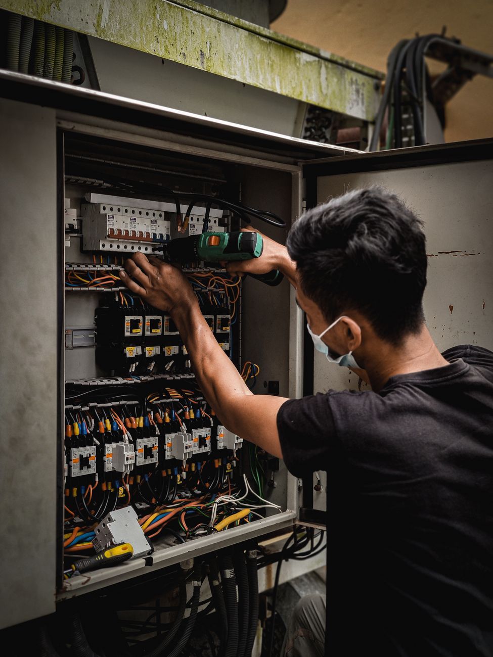 Commercial journeyman electrician working on a wiring panel, the kind of hands-on commercial-scale work this interview bank screens for.