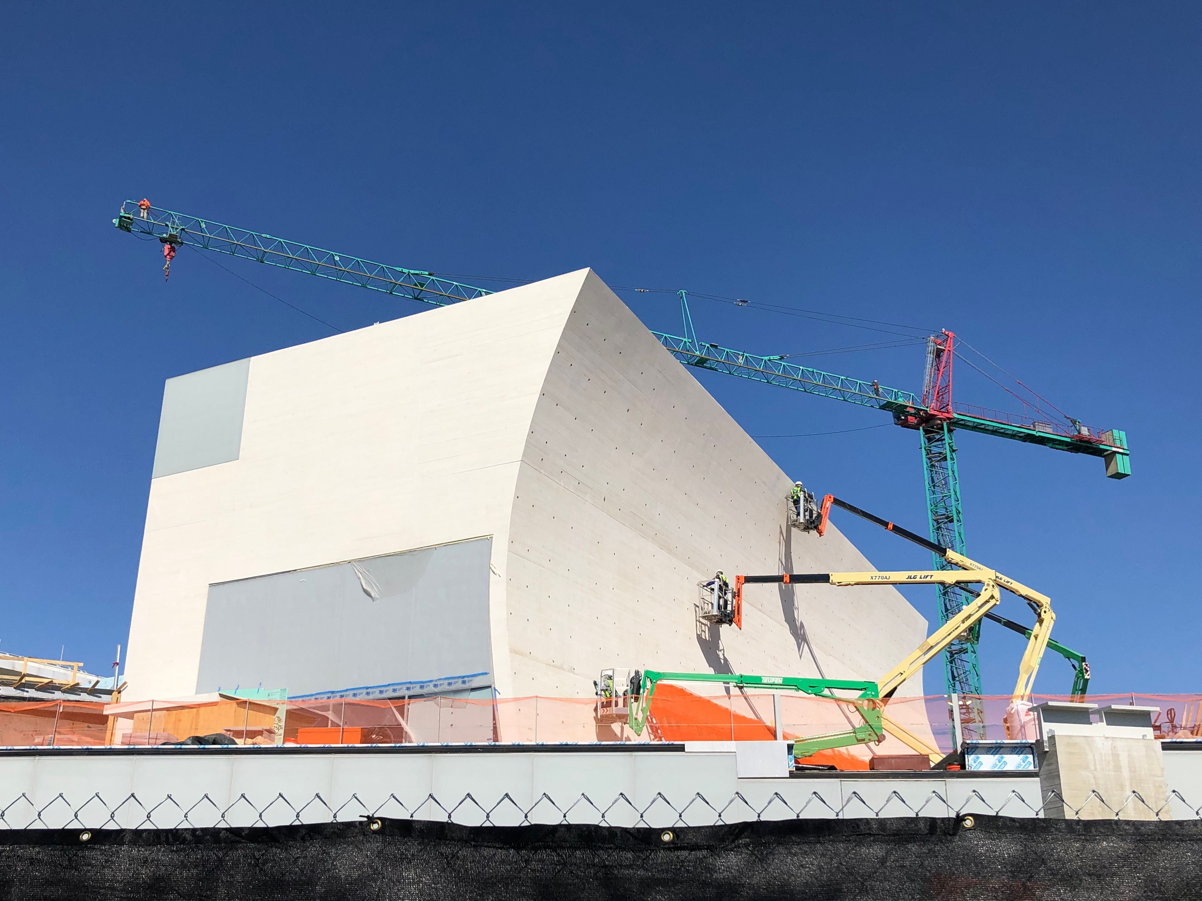 Commercial building under construction with tower cranes overhead.