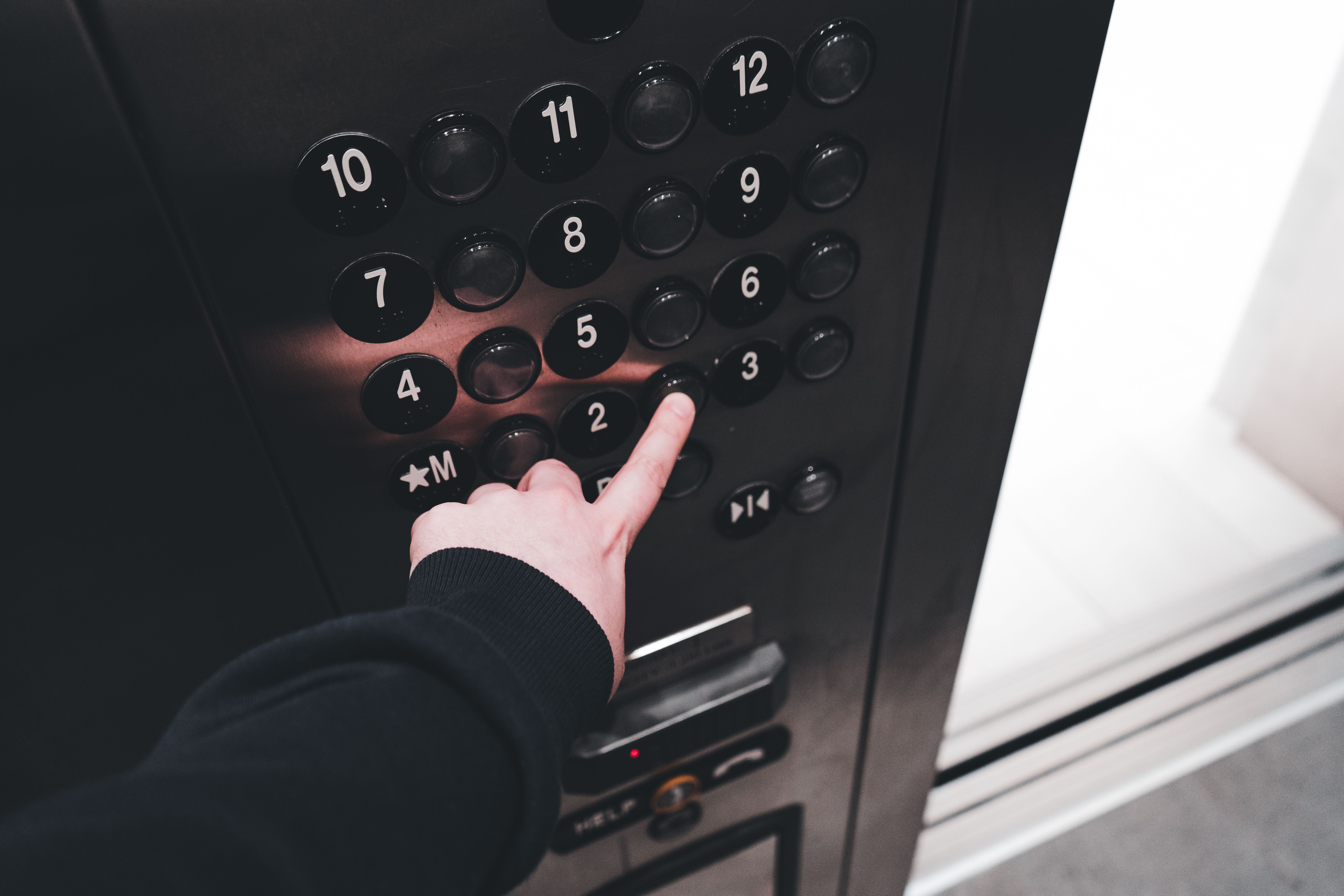 Person pressing a floor button on an elevator control panel