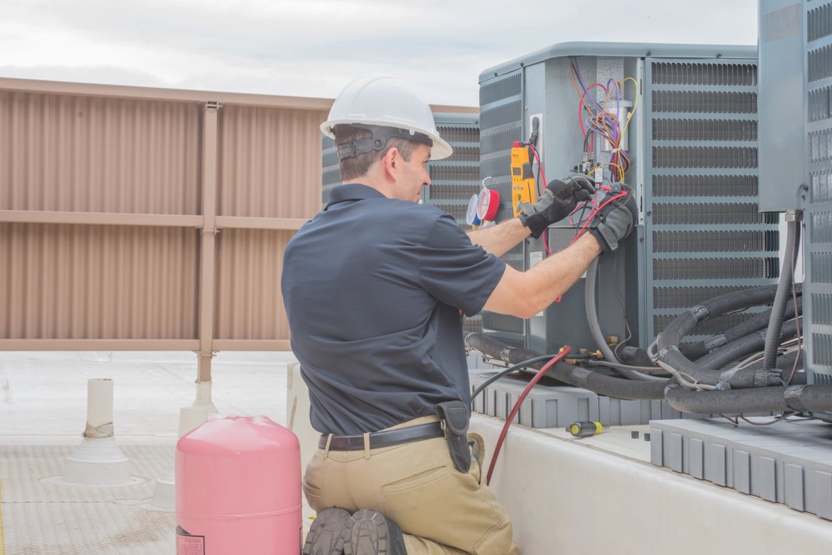 Commercial HVAC technician working on a rooftop unit — HVAC & Mechanical interview guide cover
