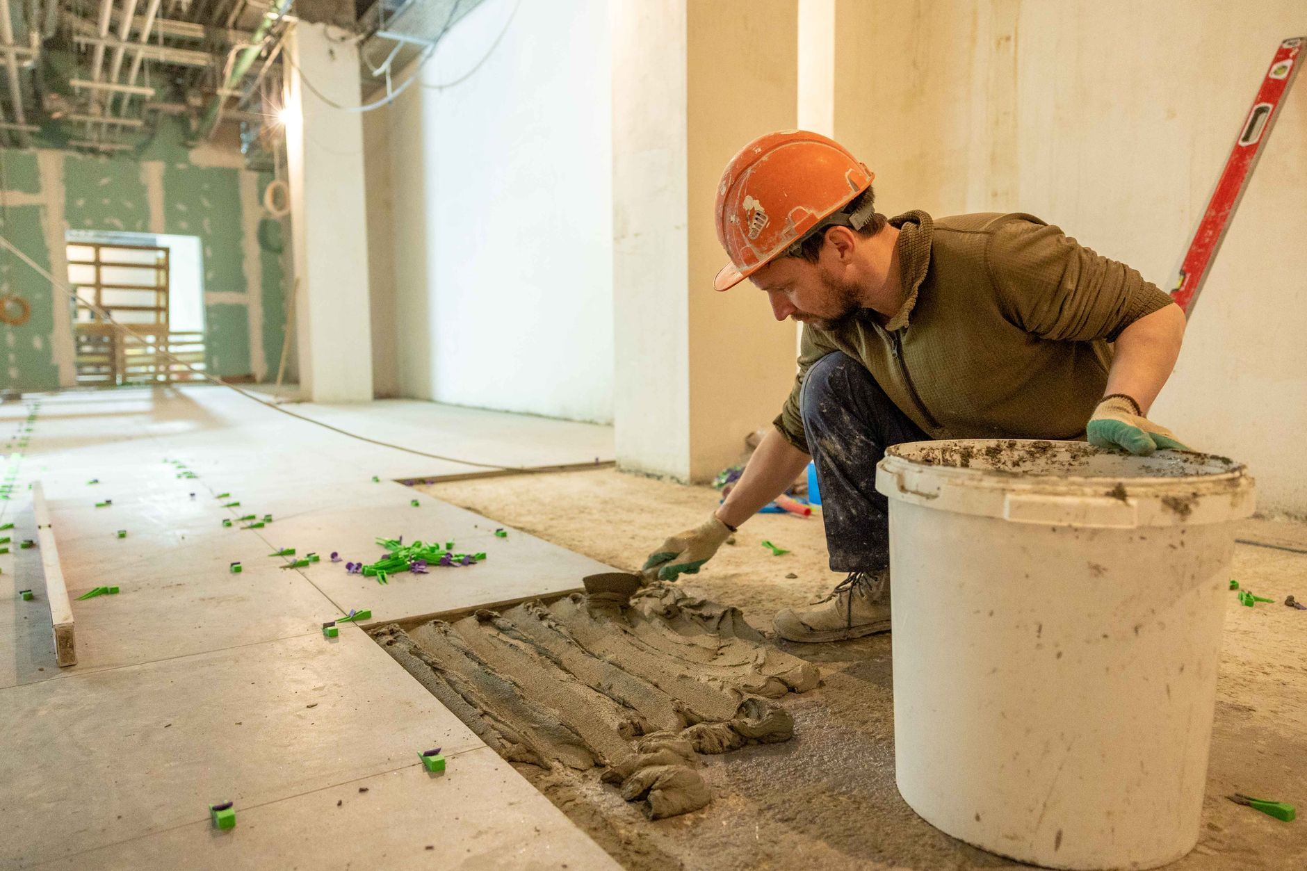 Commercial flooring installer working on substrate prep and installation, the kind of prep judgment this interview bank screens for.
