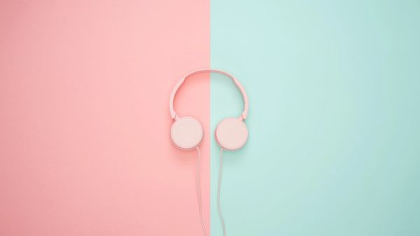 Pink headphones on a pink and blue background.