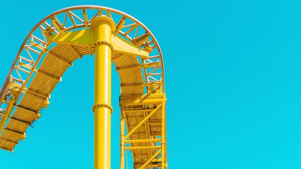 Yellow roller coaster track against a blue sky.