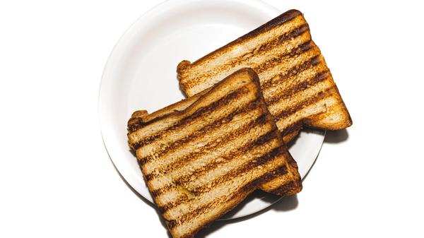 Two pieces of plain grilled toast on a white plate.