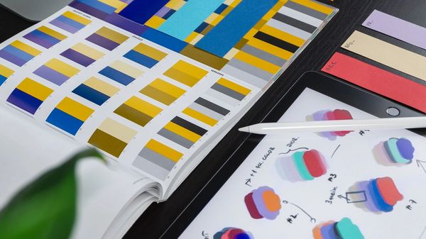 Design colour swatches on a desk with an iPad, Apple Pencil and Mac.