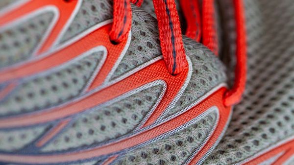 Close up of a grey running trainer with red laces.