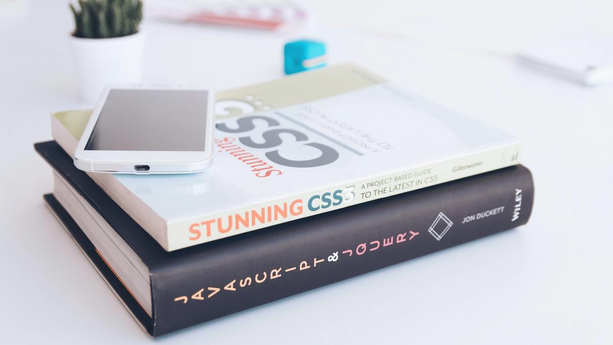 A mobile phone on top of Stunning CSS and Javascript & JQuery books.