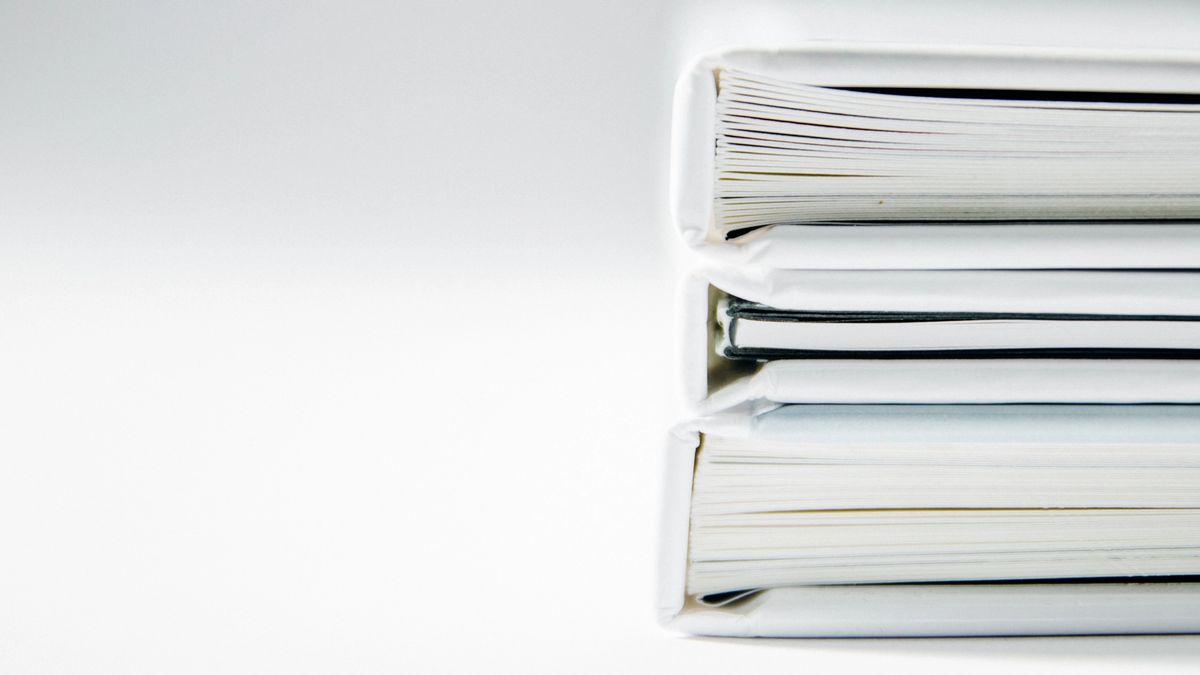 Stacked white folders full of papers on a white background