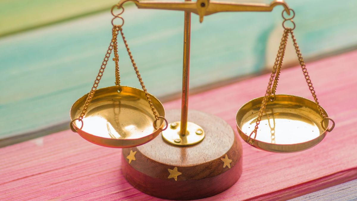 Golden balance scales on a colourful painted wooden table.