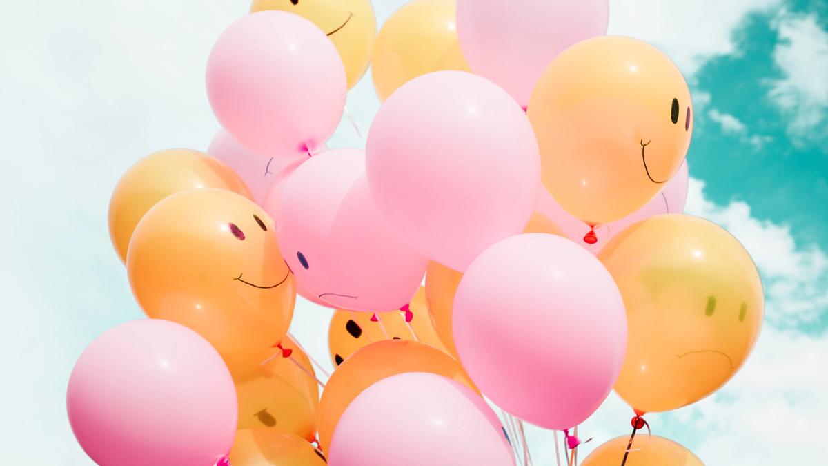 Pink and orange balloons with smiley faces on them.