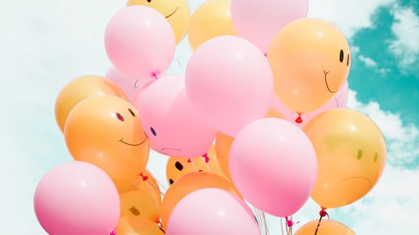 Pink and orange balloons with smiley faces on them.